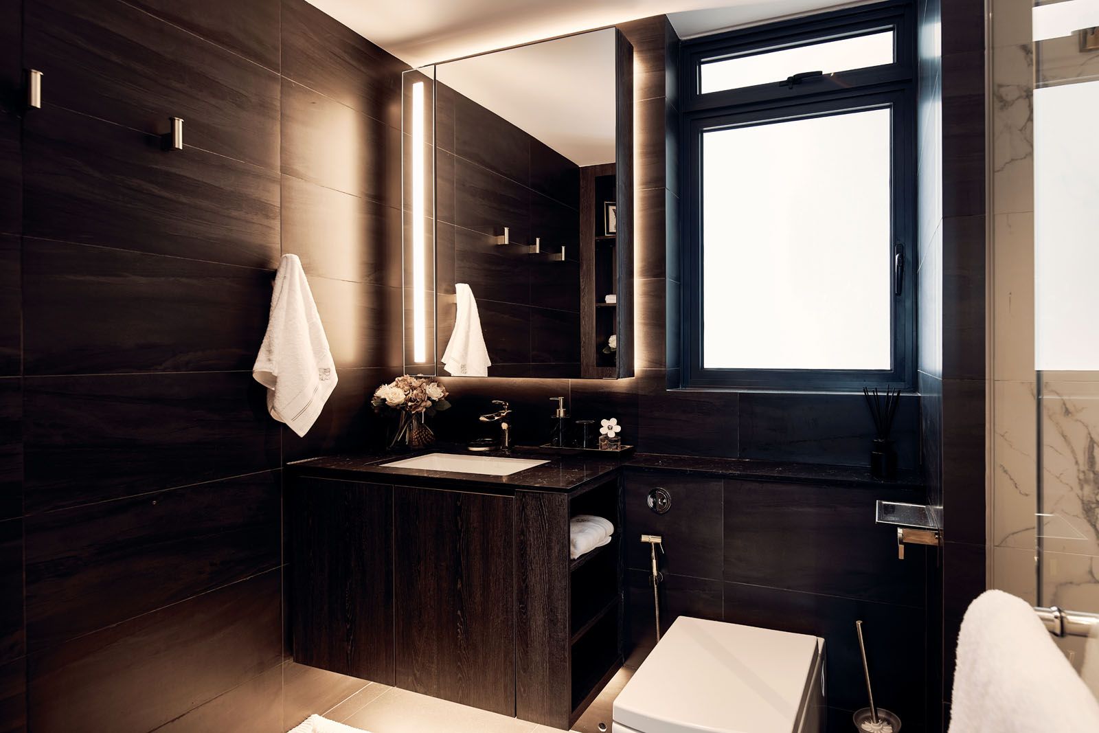 Dark wood cabinetry and light stone tiles create a minimalist look in the bathroom