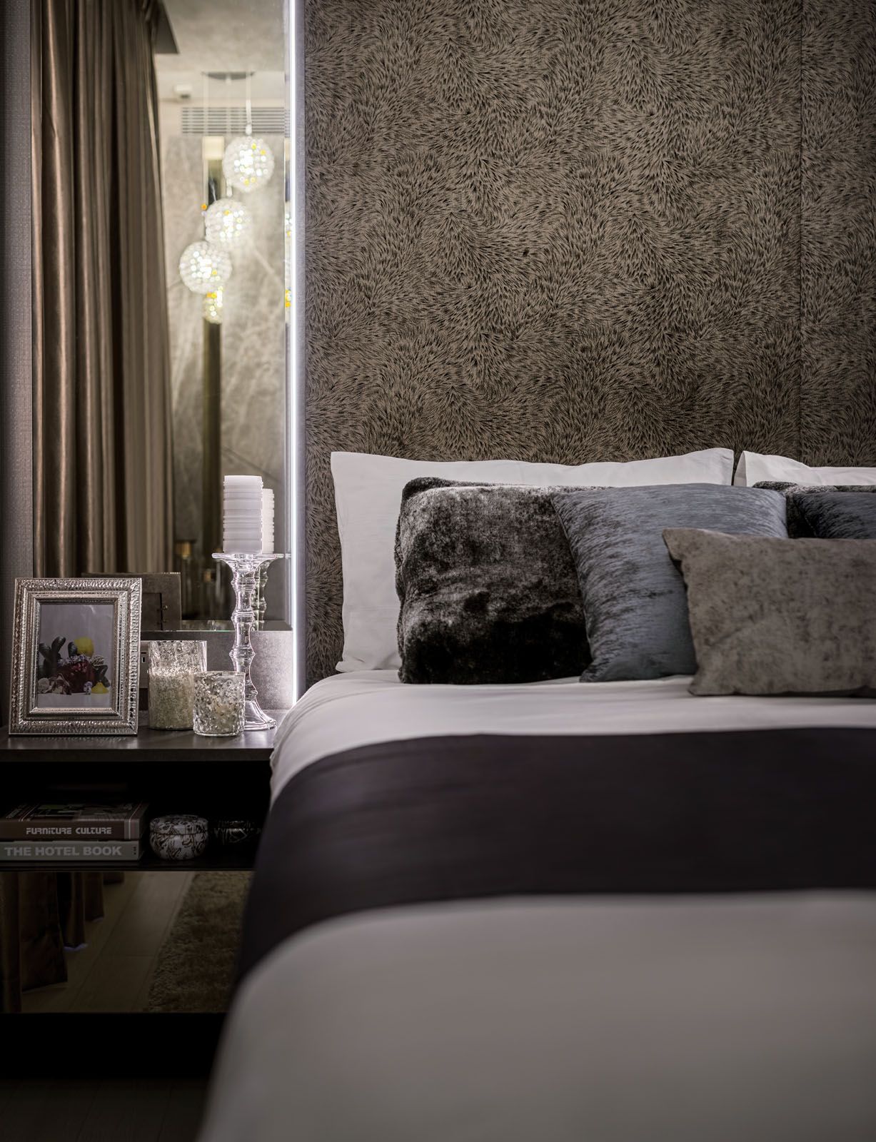The custom-made upholstered headboard extends to the full height of the bedroom