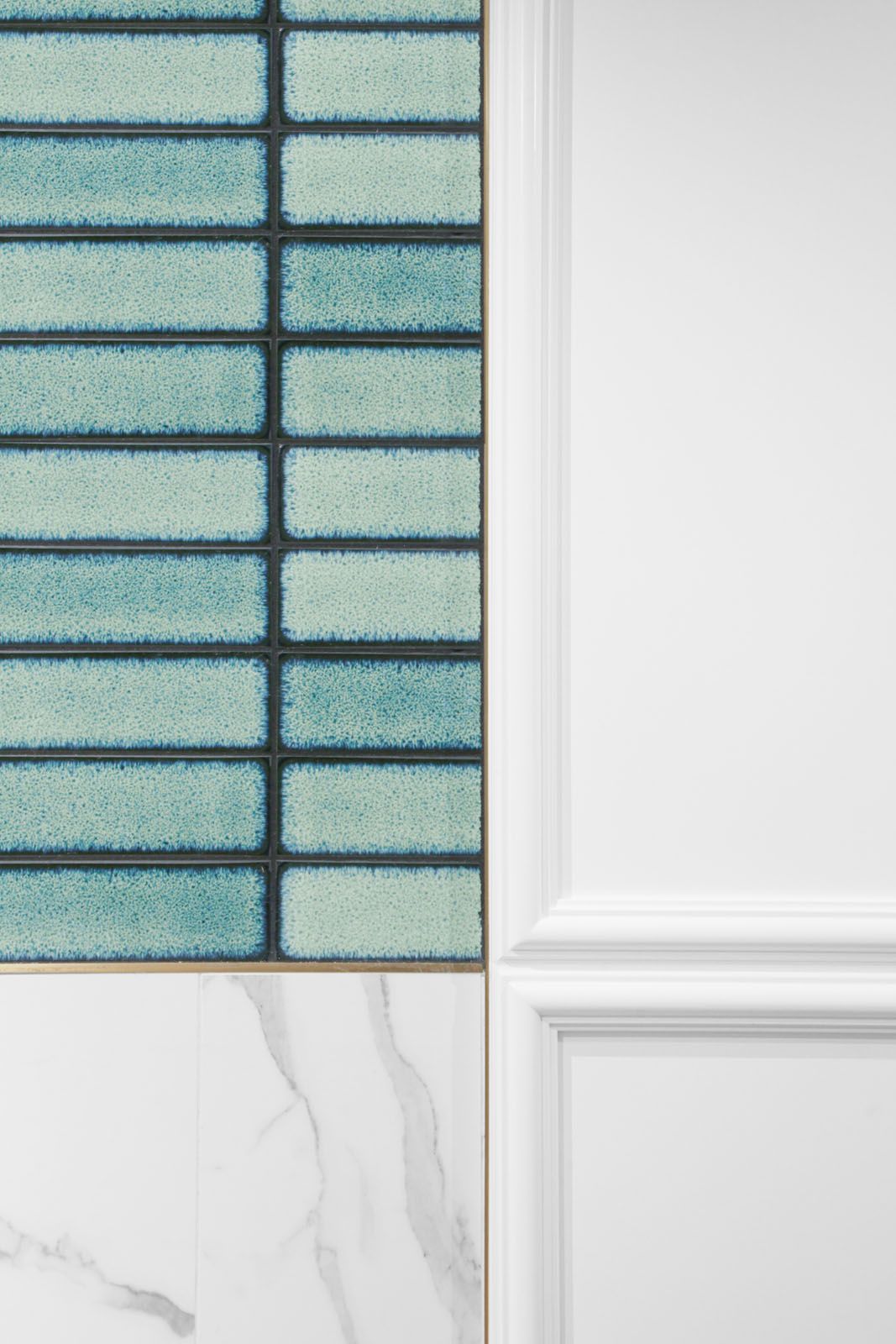 Lim + Lu pairs a mix of wainscoting with marble and glazed tiles for a bathroom area in the Colourliving showroom in Hong Kong