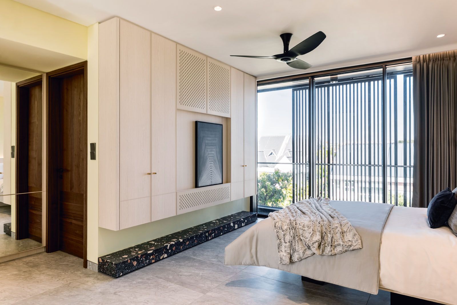 Custom-made cabinetry in walnut veneer adds to the cohesive look of the master bedrooom