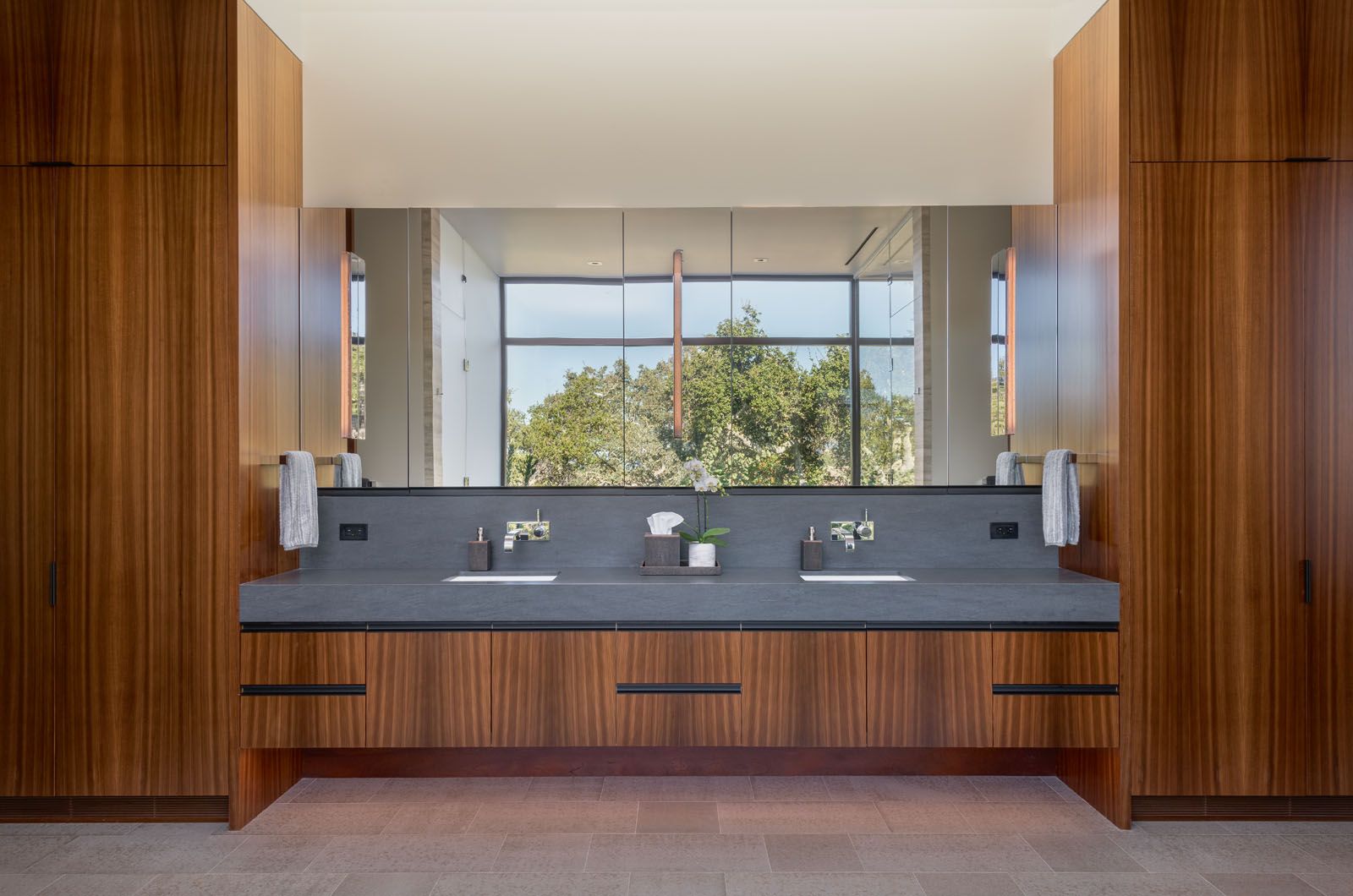 Warm wood, stone and brushed metal hardware complement the calming look of this spacious vanity area