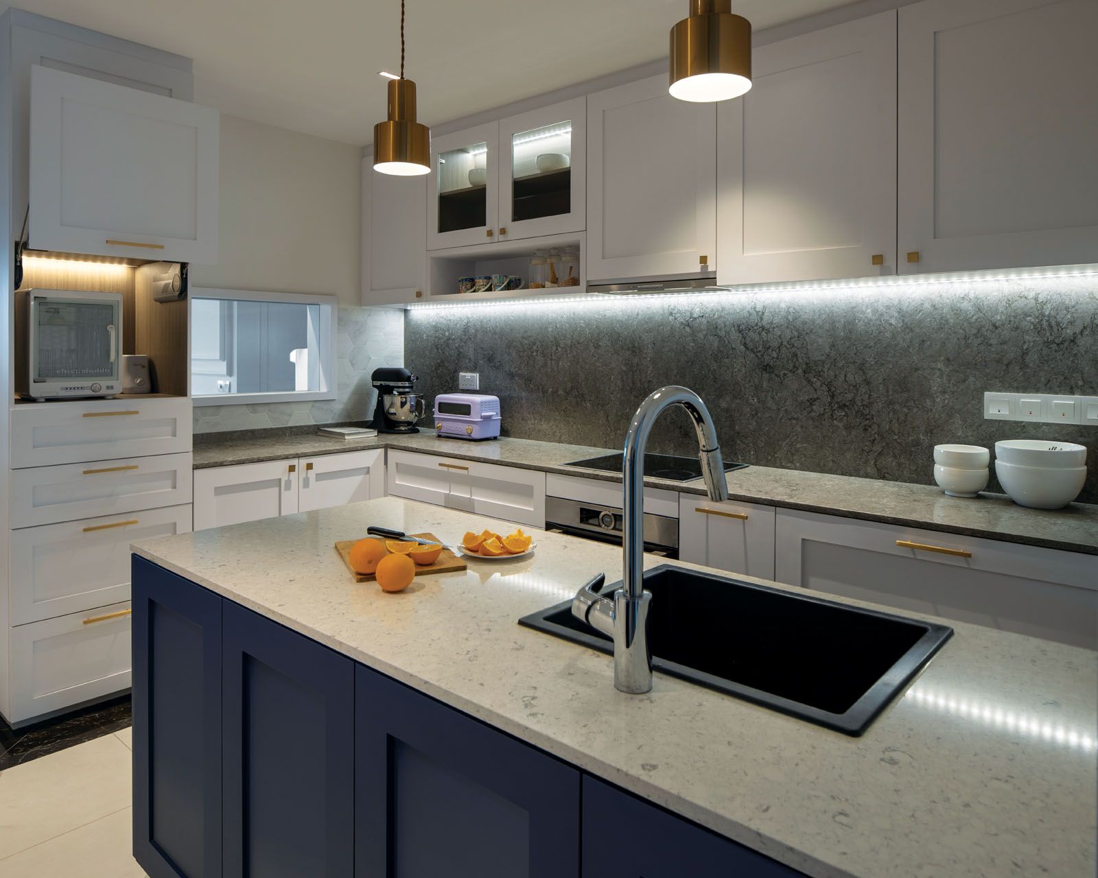 The stylish kitchen features gold hardware on white cabinetry