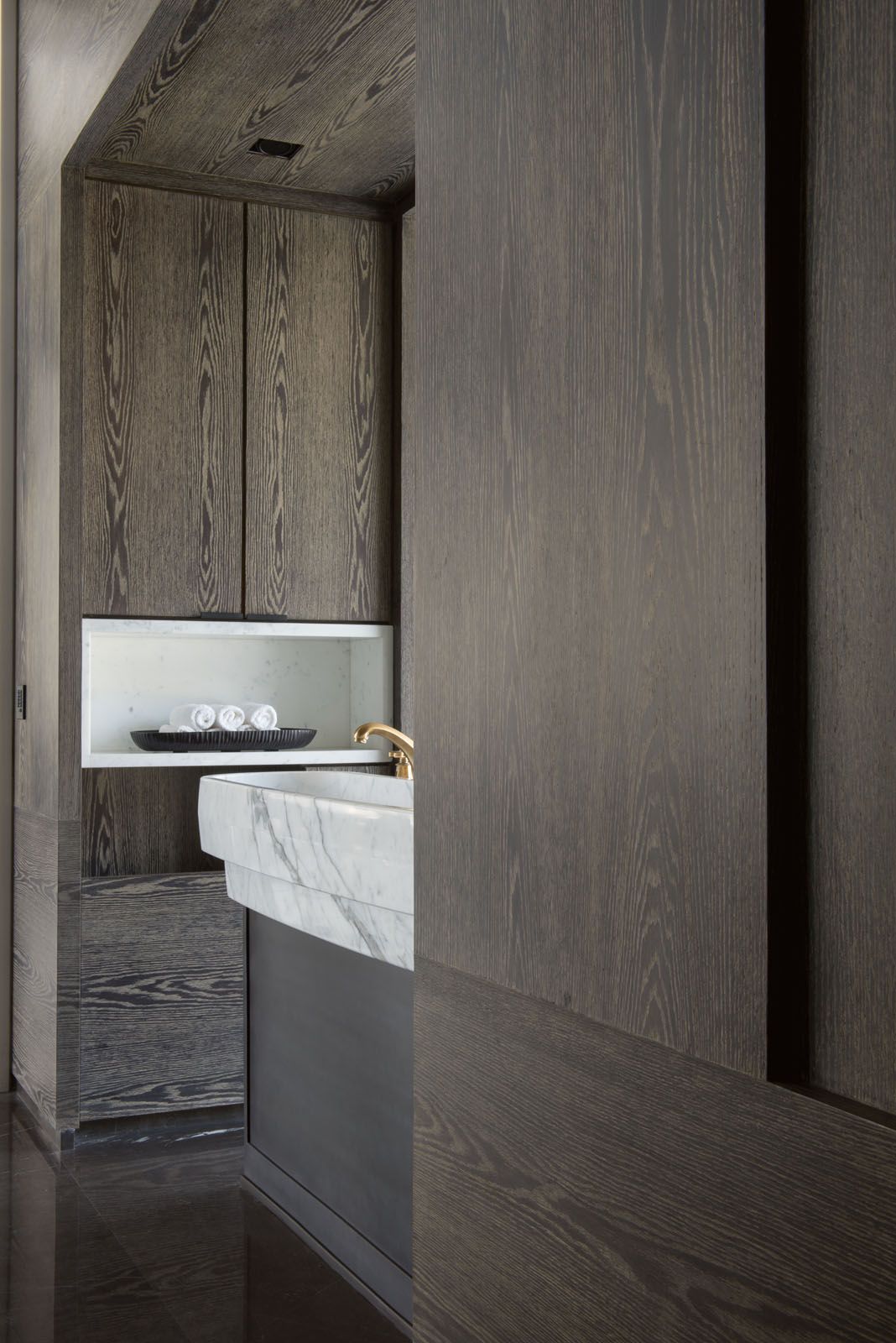 The bathroom features a sleek combination of dark wood cabinetry and marble