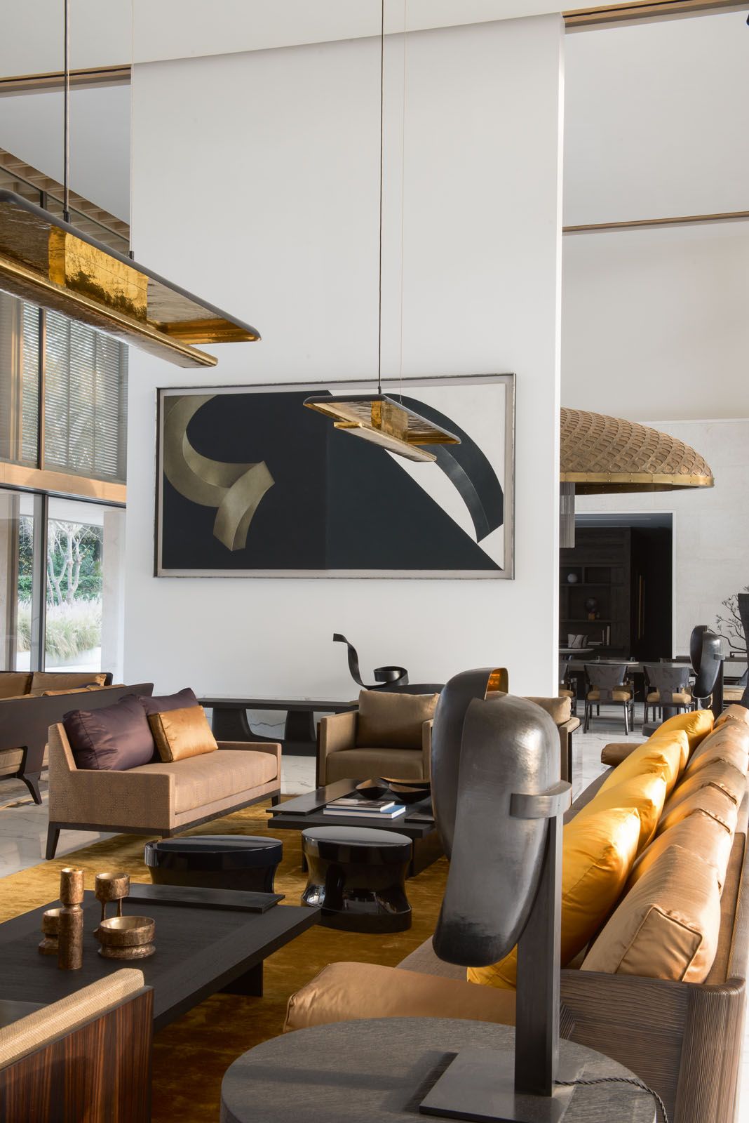 The living room features the Shelter armchairs which are upholstered in silk and cotton textiles, as well as a bespoke coffee table in wood and bronze, and ceiling lamps crafted in bronze and brass