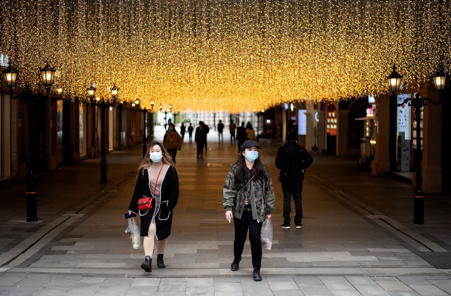 People wearing face masks walk along Hanjie shopping street in Wuhan, in China's central Hubei province on April 3, 2020. - Wuhan, the central Chinese city where the coronavirus first emerged last year, partly reopened on March 28 after more than two months of near total isolation for its population of 11 million. (Photo by NOEL CELIS / AFP)