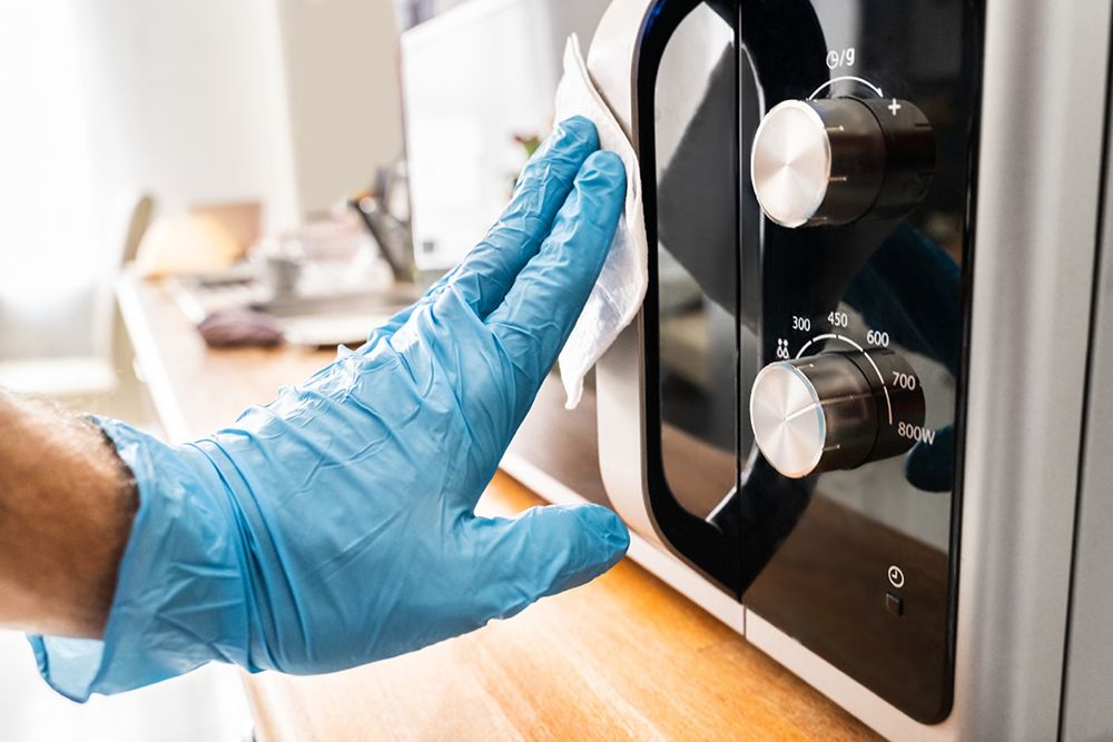 Man Wiping Microwave Oven Handle With Sanitizer Against Virus Infection