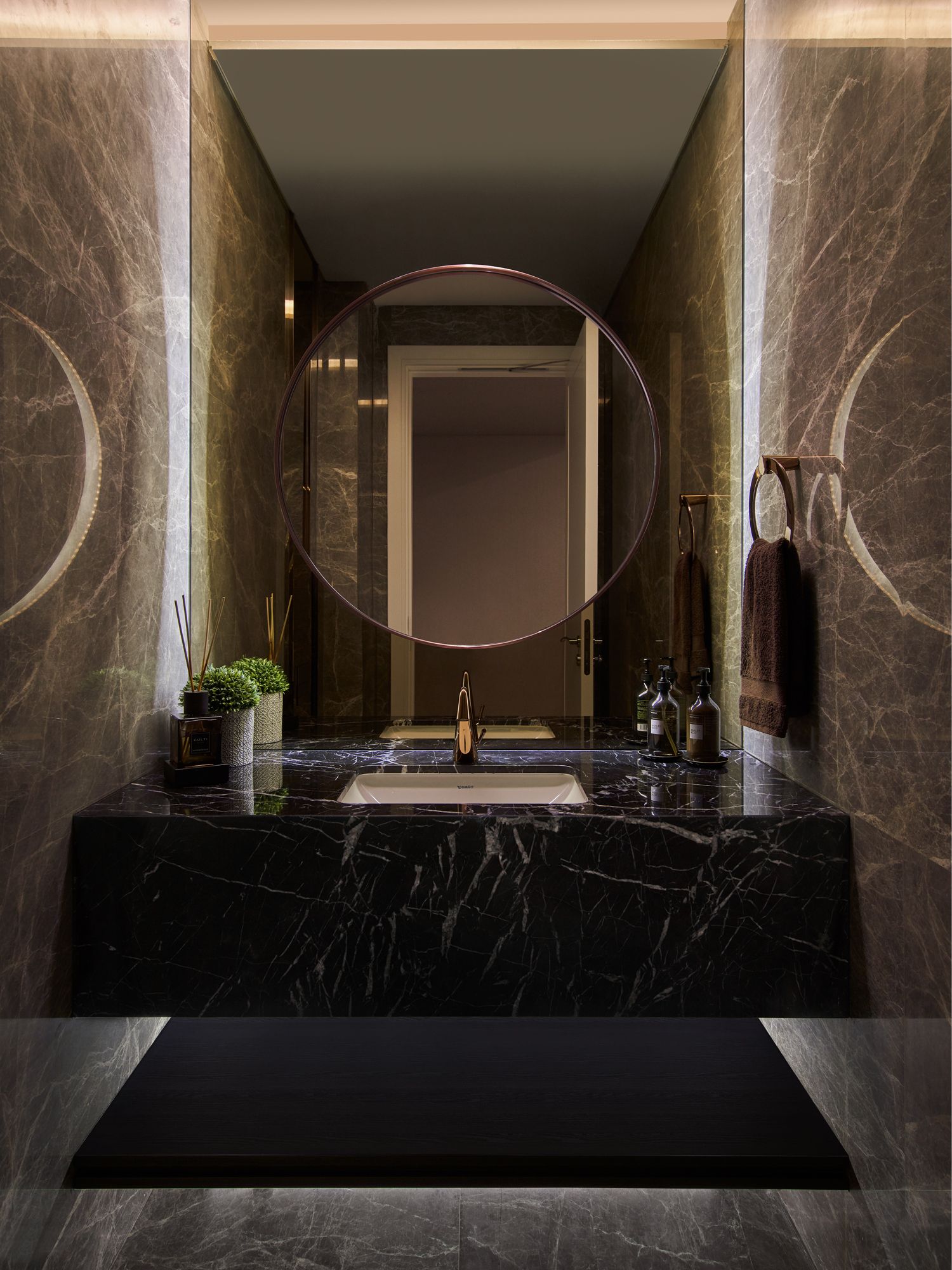 The powder room features a solid block of black marble for the basin and mirrored walls that visually expand its dimensions