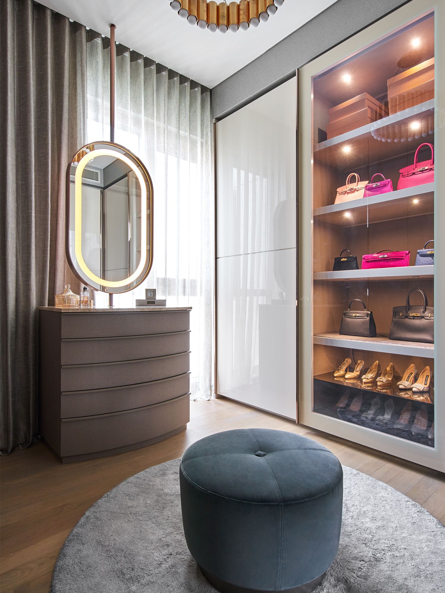 The walk-in wardrobe features cabinetry with gold trimming and built-in lighting to showcase the wife's favourite bags and shoes