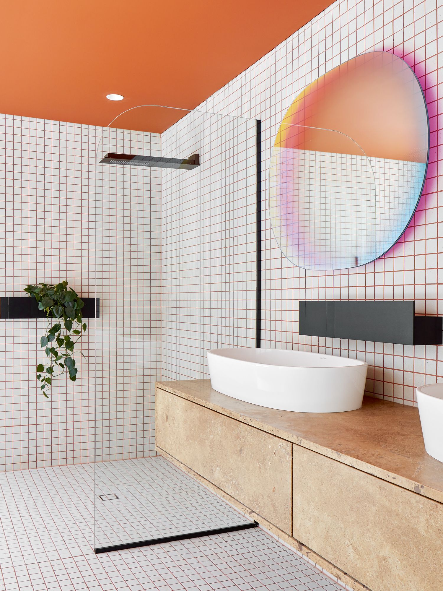 The tangerine ceiling and the iridescent Shimmer mirror from Glas Italia create visual interest in this bathroom