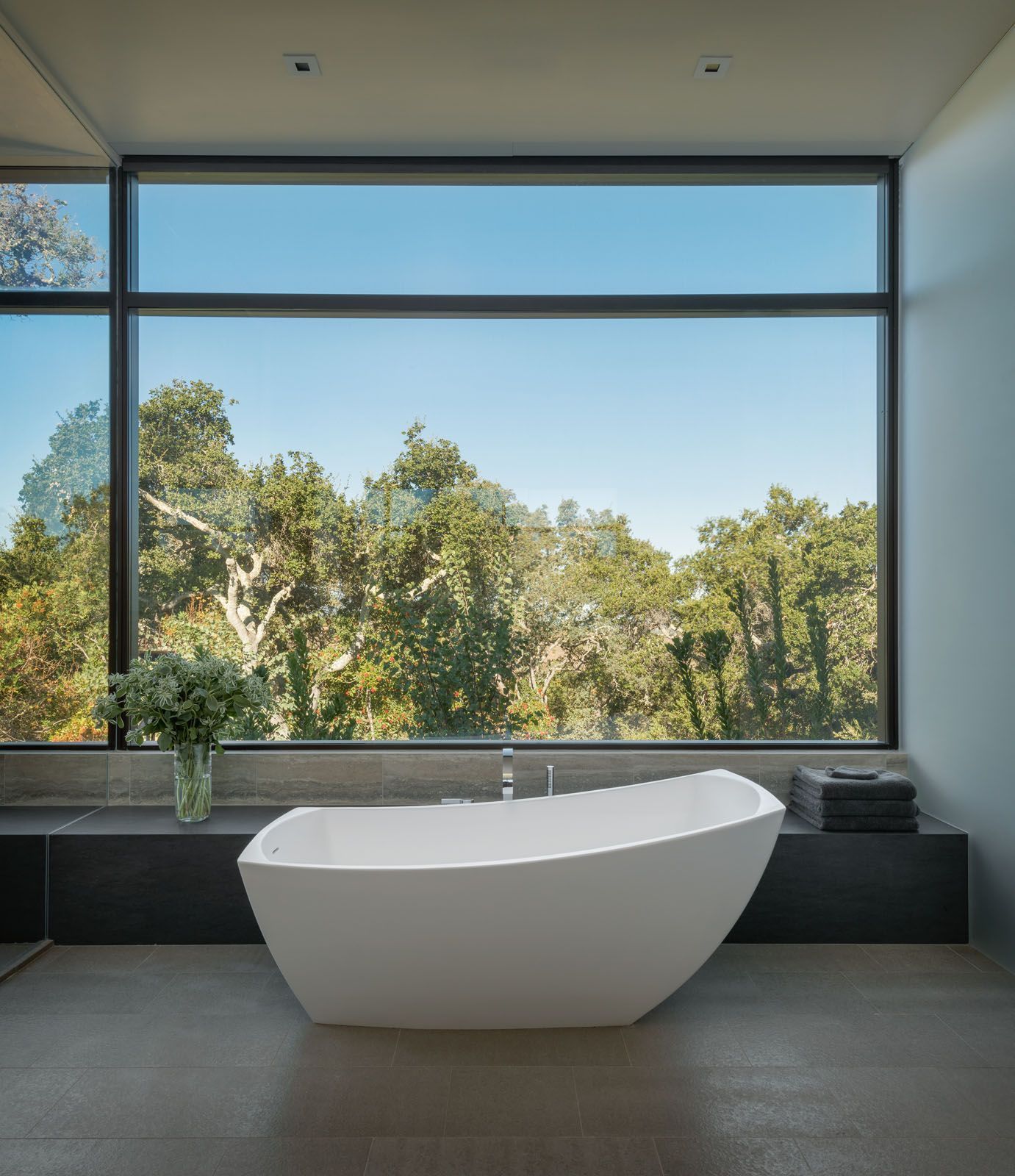 This master bathroom in a California home contains a sculptural bathtub that overlooks a panoramic treetop view