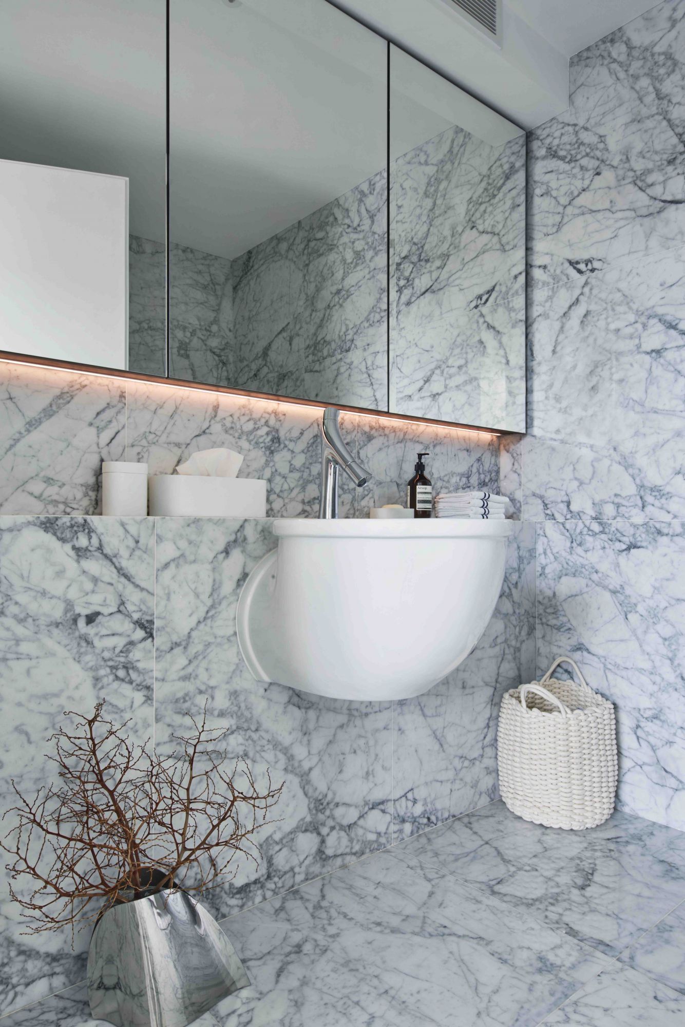 The light marble tiles on the wall and flooring in this powder room by EHKA Studio creates a clean and contemporary impression (Photography: Jasper Yu)