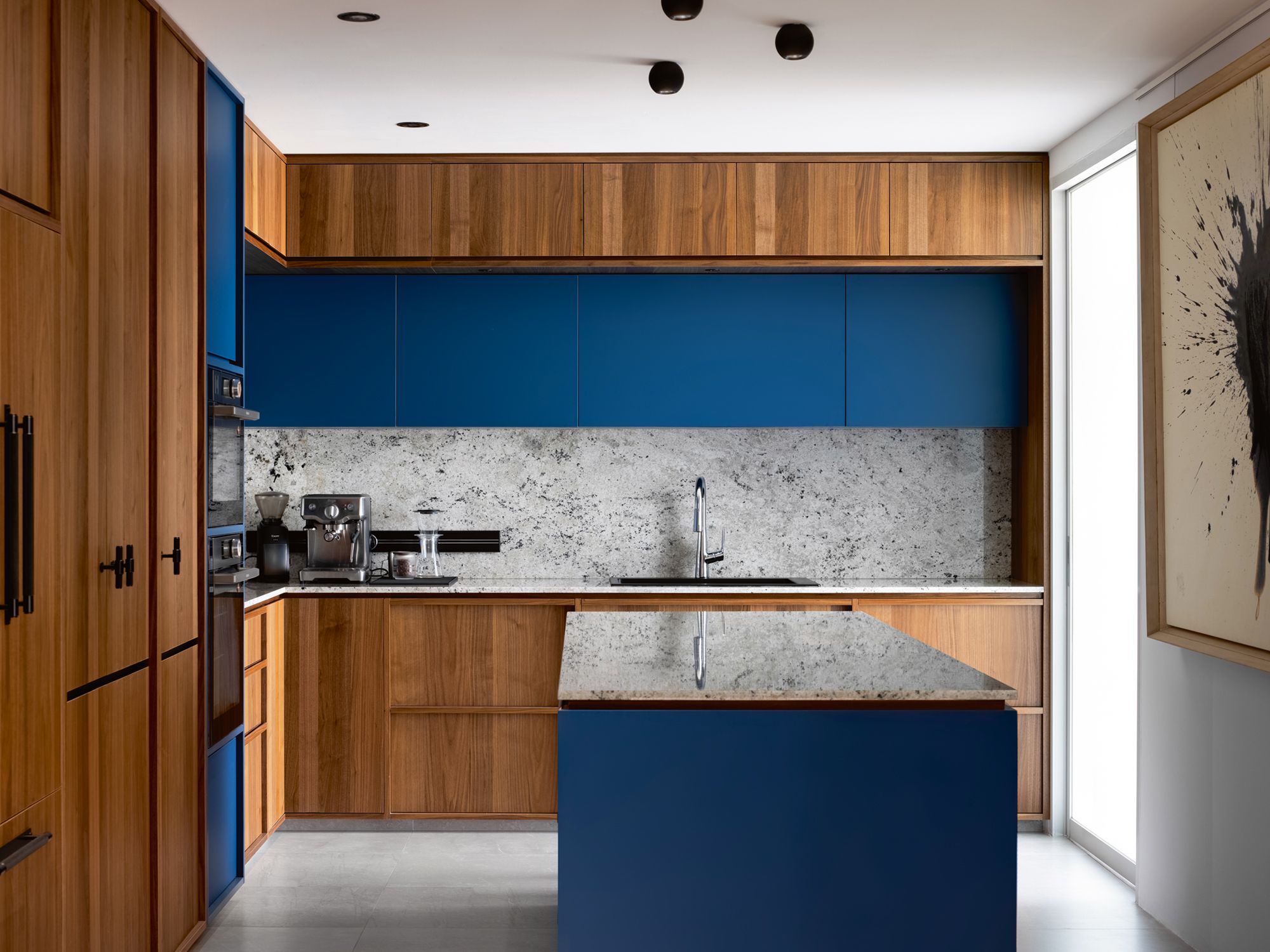 Blue cabinetry and the rugged texture of the backsplash make the kitchen pop