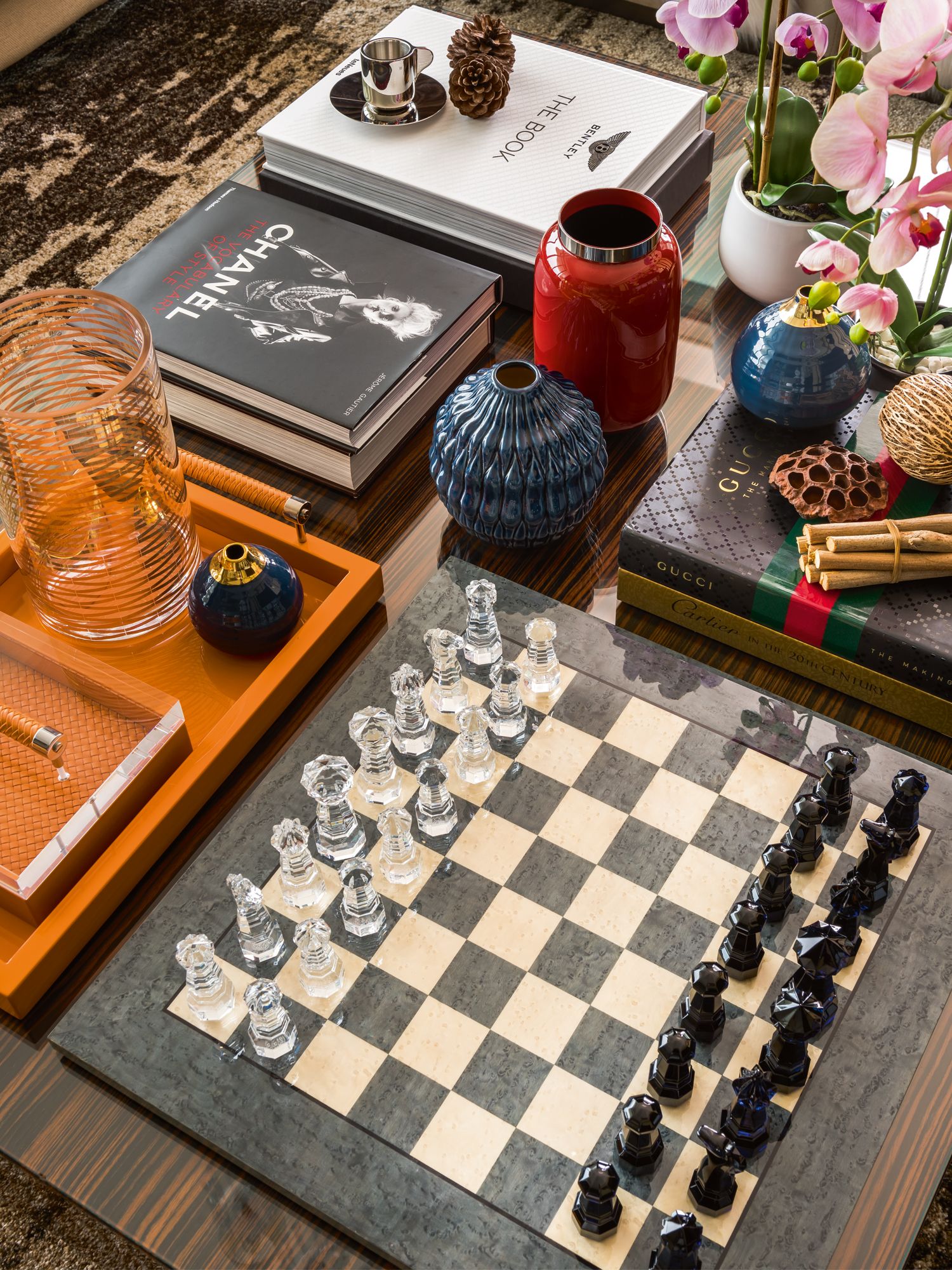 Orchids contribute to the array of decorative items and books on a coffee table styled by Prestige Global Designs