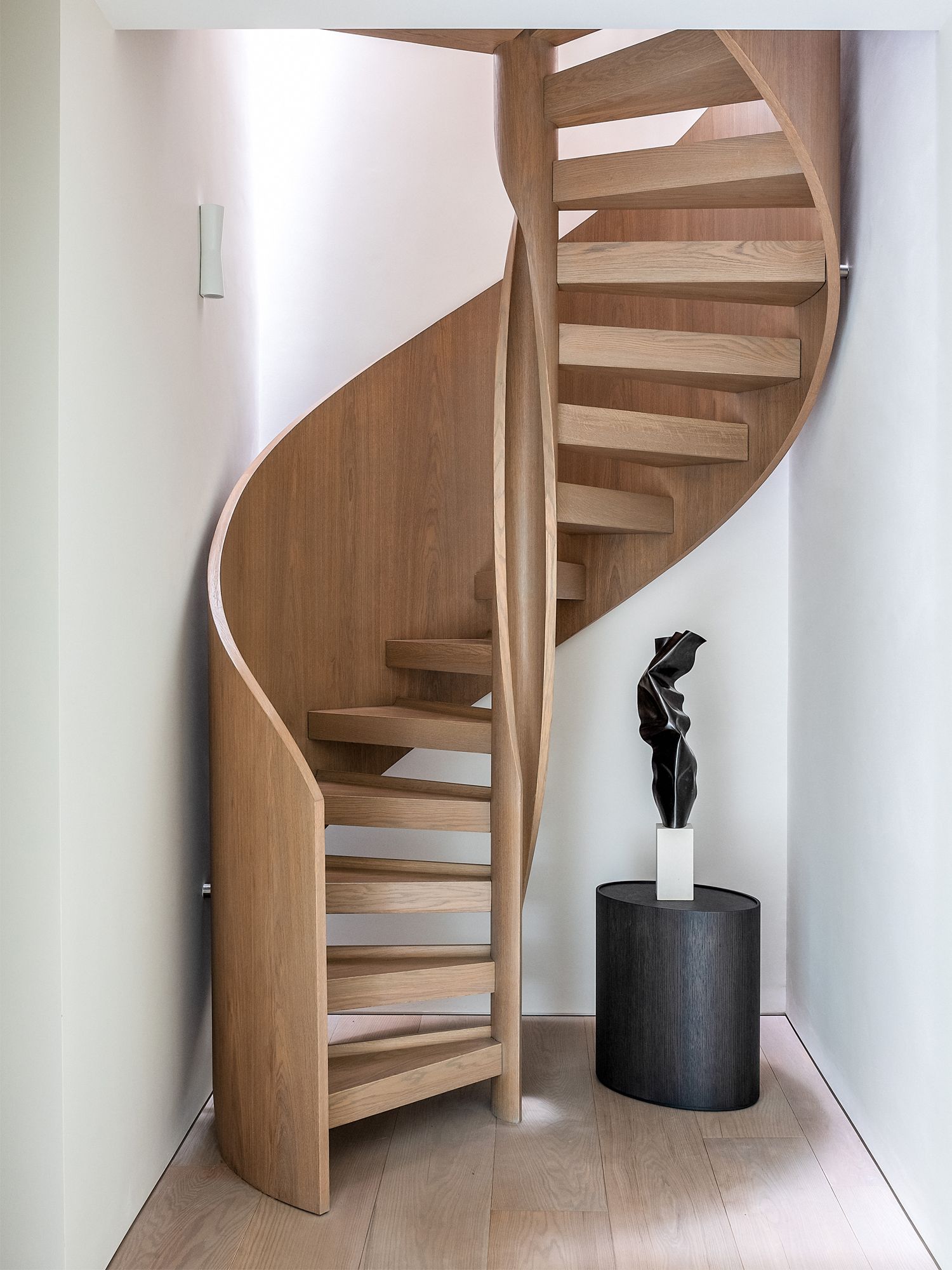The spiral staircase forms a connection between the three levels, with a sculpture by Francesco Moretti adding an artistic touch to the space