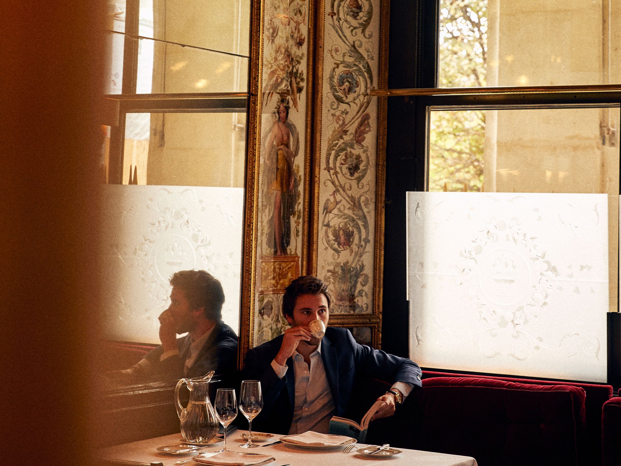 Antique dealer Guillaume Léage enjoying a drink at a chic Parisian café, giving a taste of Parisian life (Image: Oliver Pilcher, courtesy of Assouline)