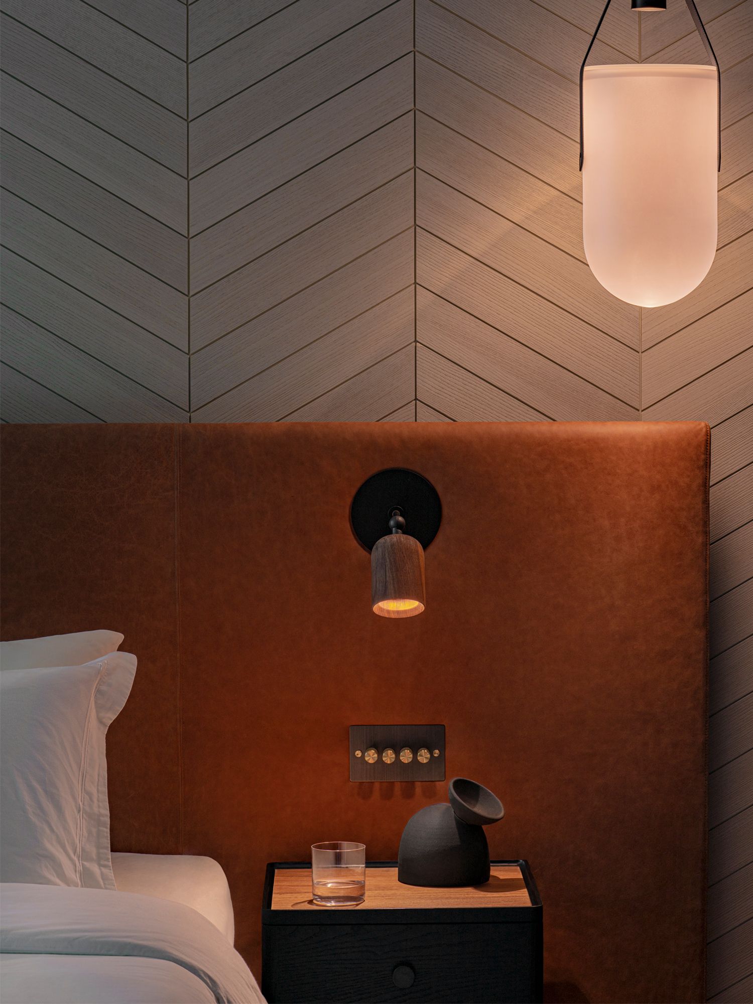 One side of the bedroom is lit up by a pendant lamp from Allied Maker