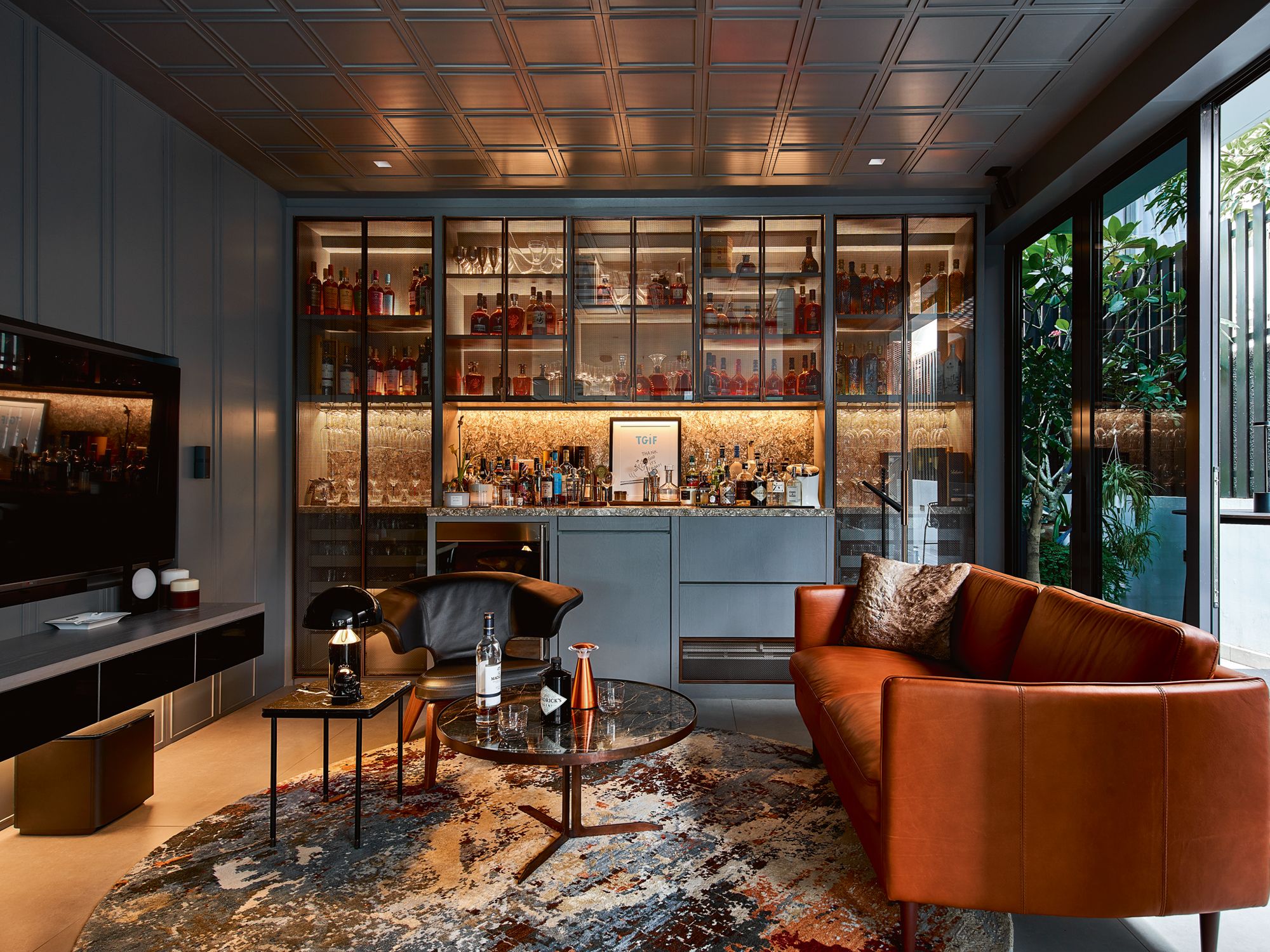 The drinking lounge is a handsome space with a backlit glass cabinet that showcases the husband’s treasured spirits