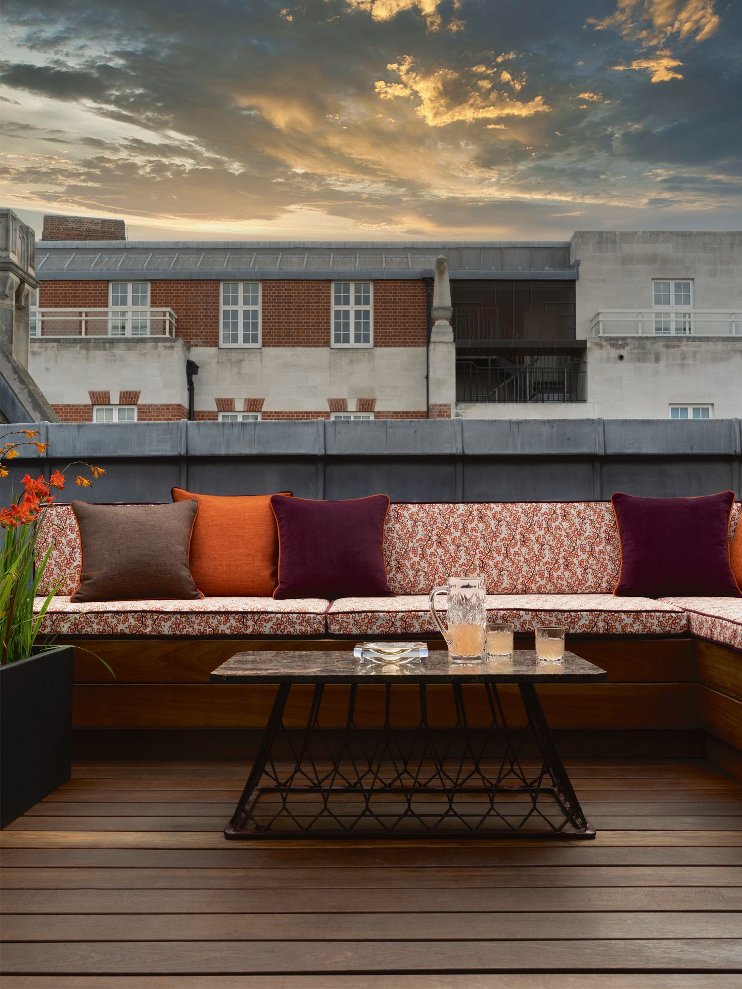 This balcony echoes the rich hues of the adjoining guest bedroom with colourful accent cushions and the botanical-patterned upholstery of the bespoke bench