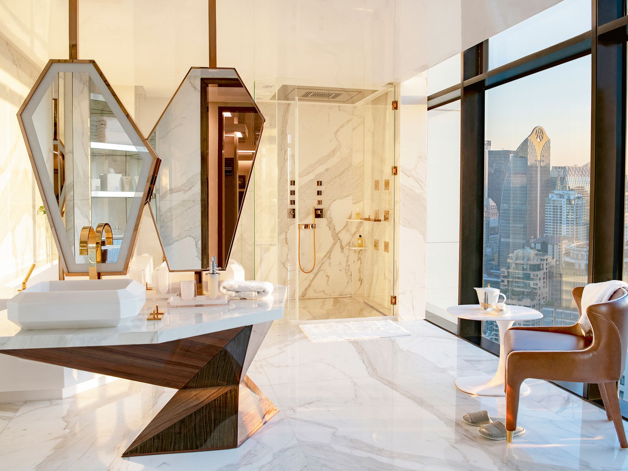 The glamorous master bathroom in this Bangkok penthouse features a sculptural marble vanity and incredible views of the city