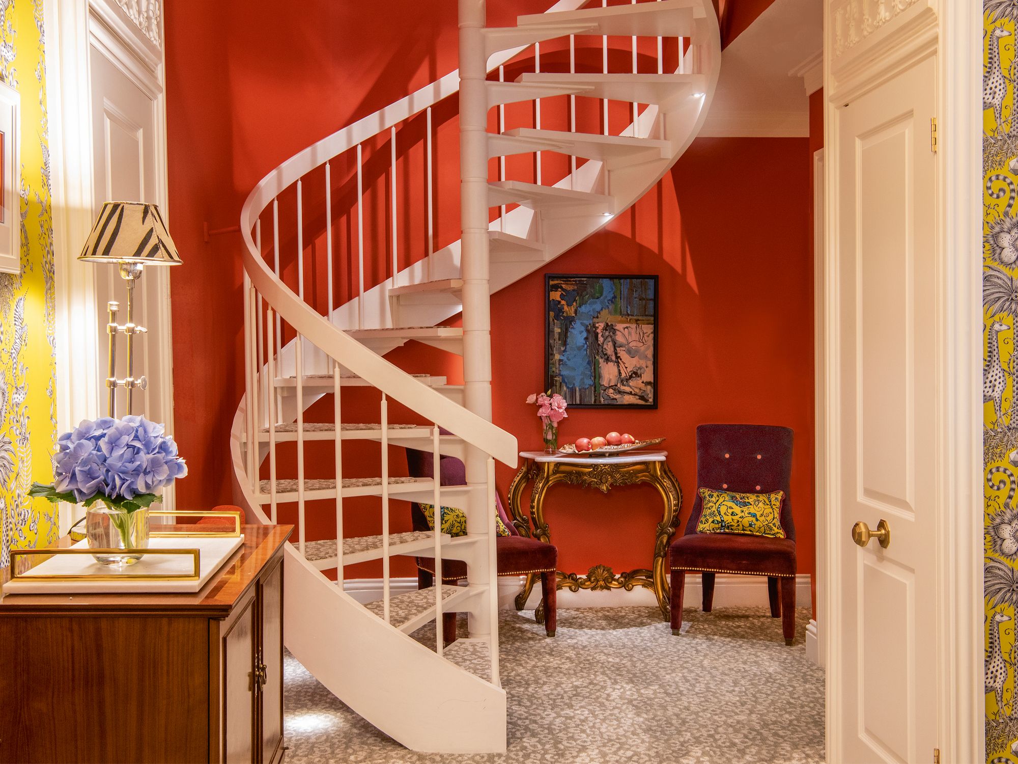 The tangerine wall colour livens up the alcove behind the spiral staircase