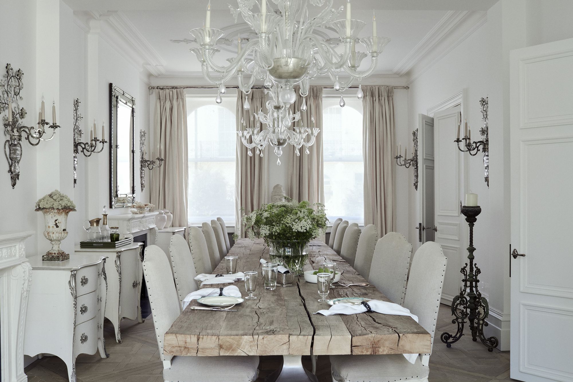 The dining room features side storage units from Moissonnier, accompanied by antique wall lights from Maison Baguès and a collection of vintage finds from Henry