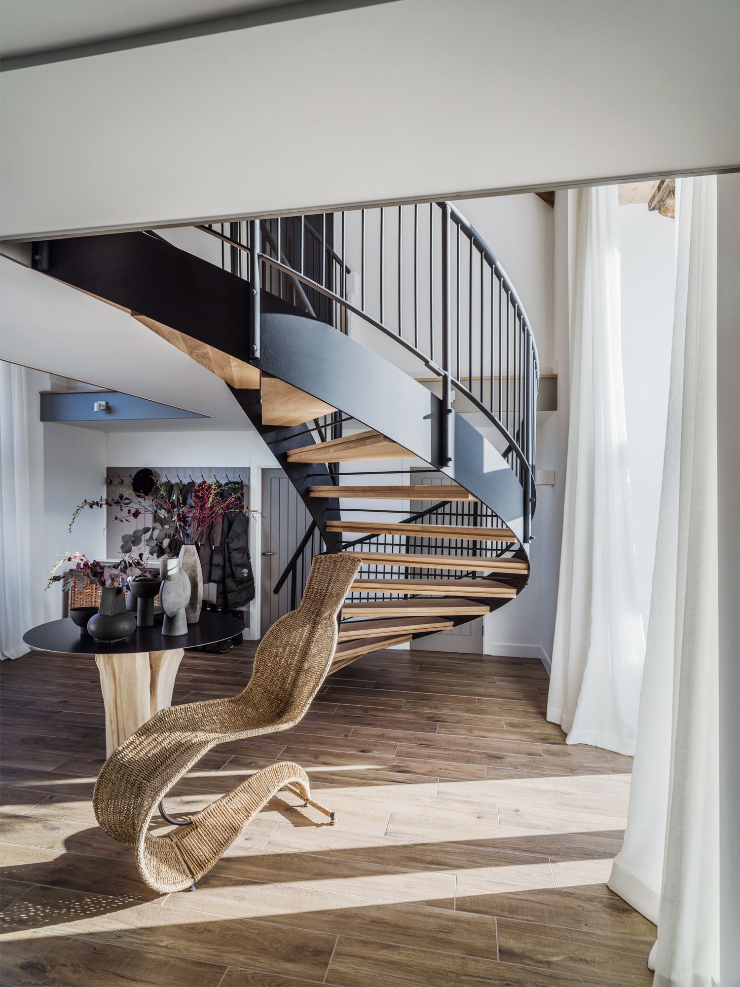 Original wooden beams and dark-toned railing contrast with the immaculate white walls