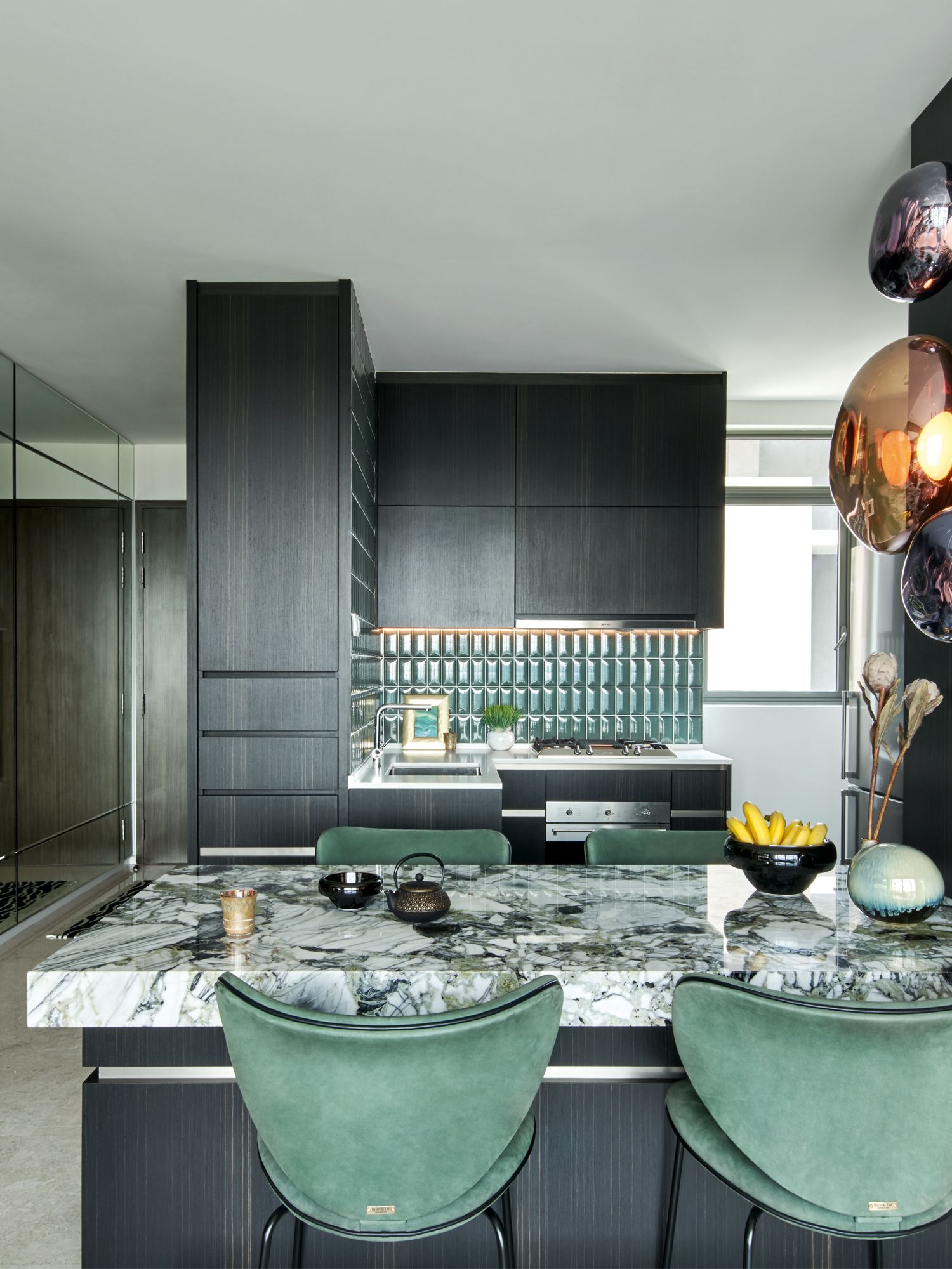 The dining chairs and tiles on the kitchen backsplash feature matching green tones