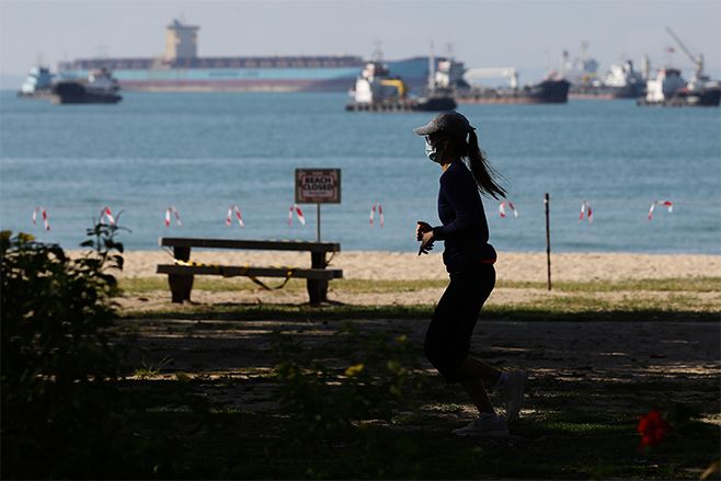 A woman wearing protective mask jogs at East Coast Park. Photo: Suhaimi Abdullah/Getty Images