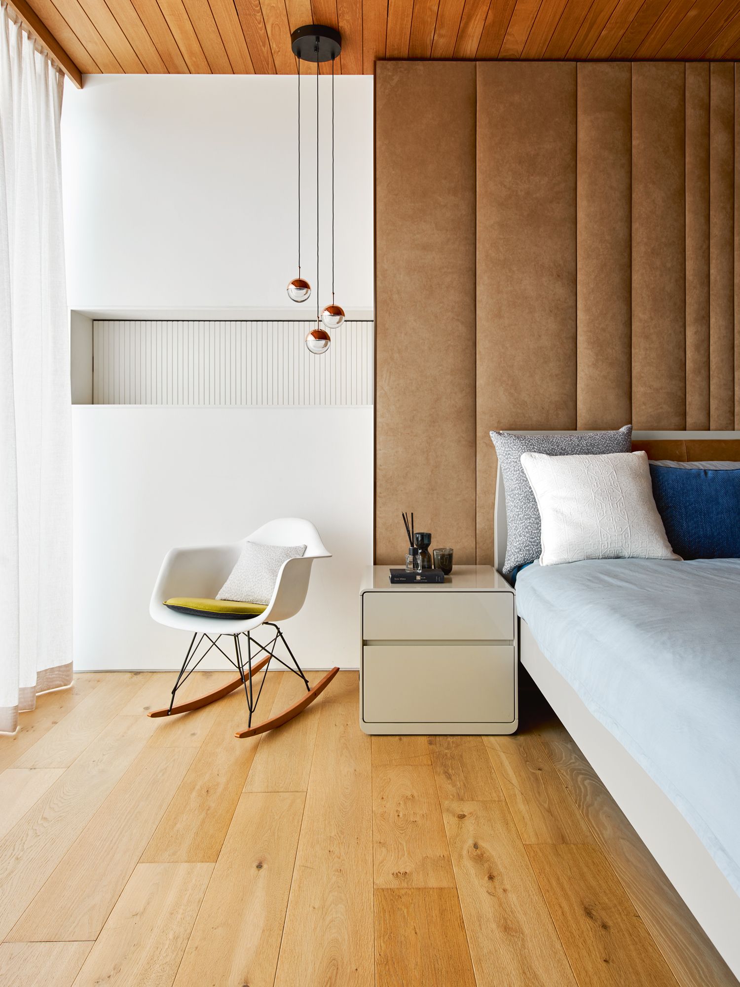 Upholstered wall panels and sheer curtains contribute to the cocooning feel of the master bedroom