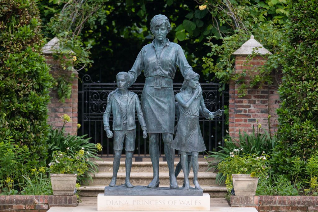 LONDON, ENGLAND - JULY 01: The statue of Diana, Princess of Wales, by artist Ian Rank-Broadley, in the Sunken Garden at Kensington Palace. The bronze statue depicts the princess surrounded by three children to represent the "universality and generational impact" of her work. Her short cropped hair, style of dress and portrait are based on the final period of her life. Beneath the statue is a plinth engraved with her name and the date of the unveiling, and in front is a paving stone engraved with an extract