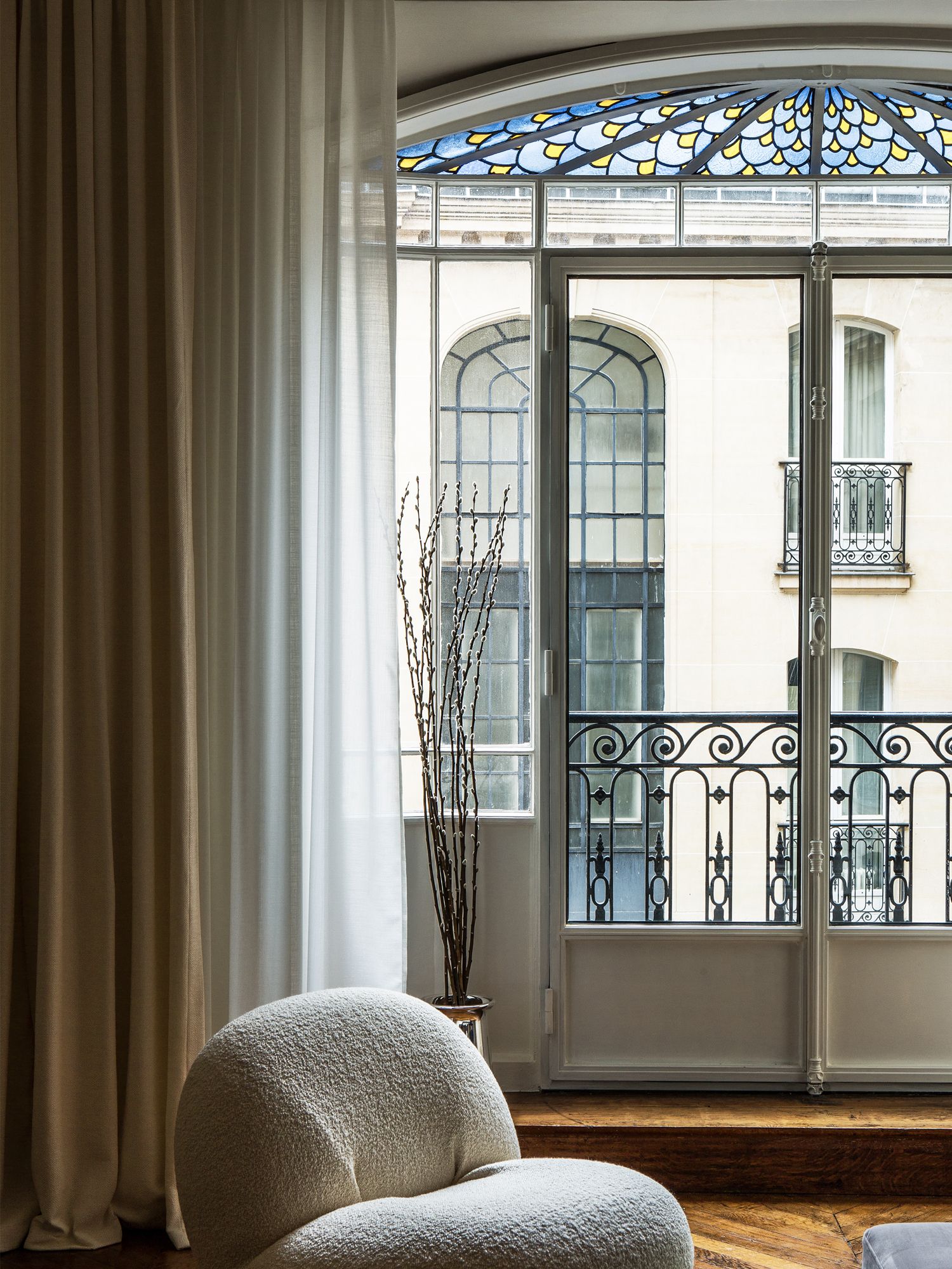 The colours on the glasswork of the bow window inspired the colour palette of this Parisian apartment