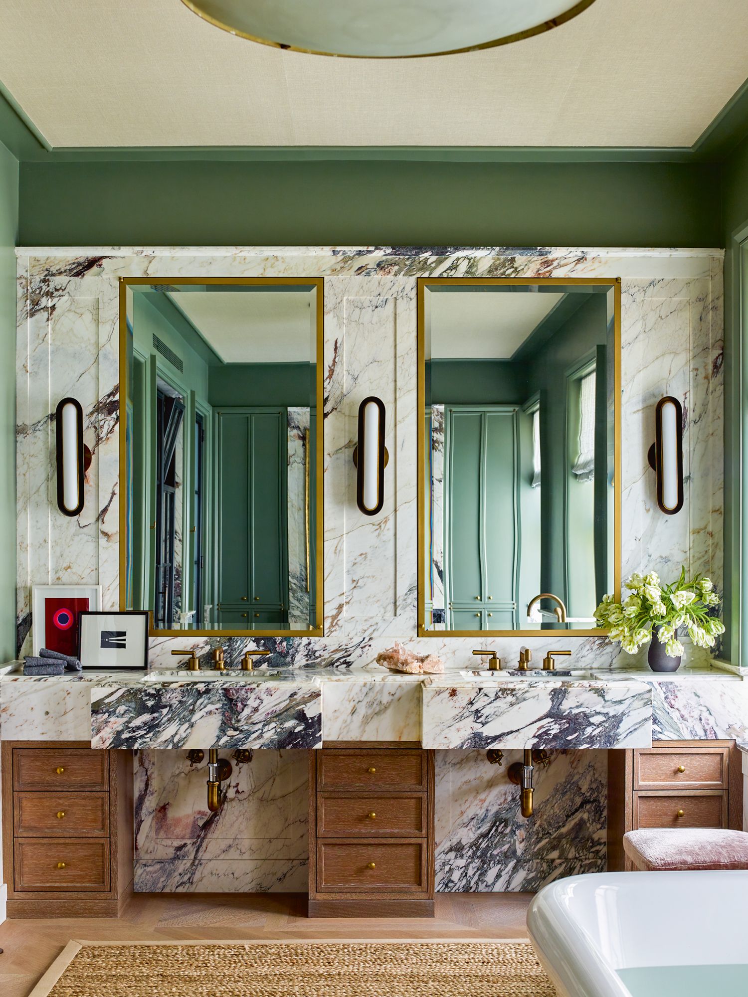 Sage green walls work as a striking foil in the master bathroom, which also features oak drawers