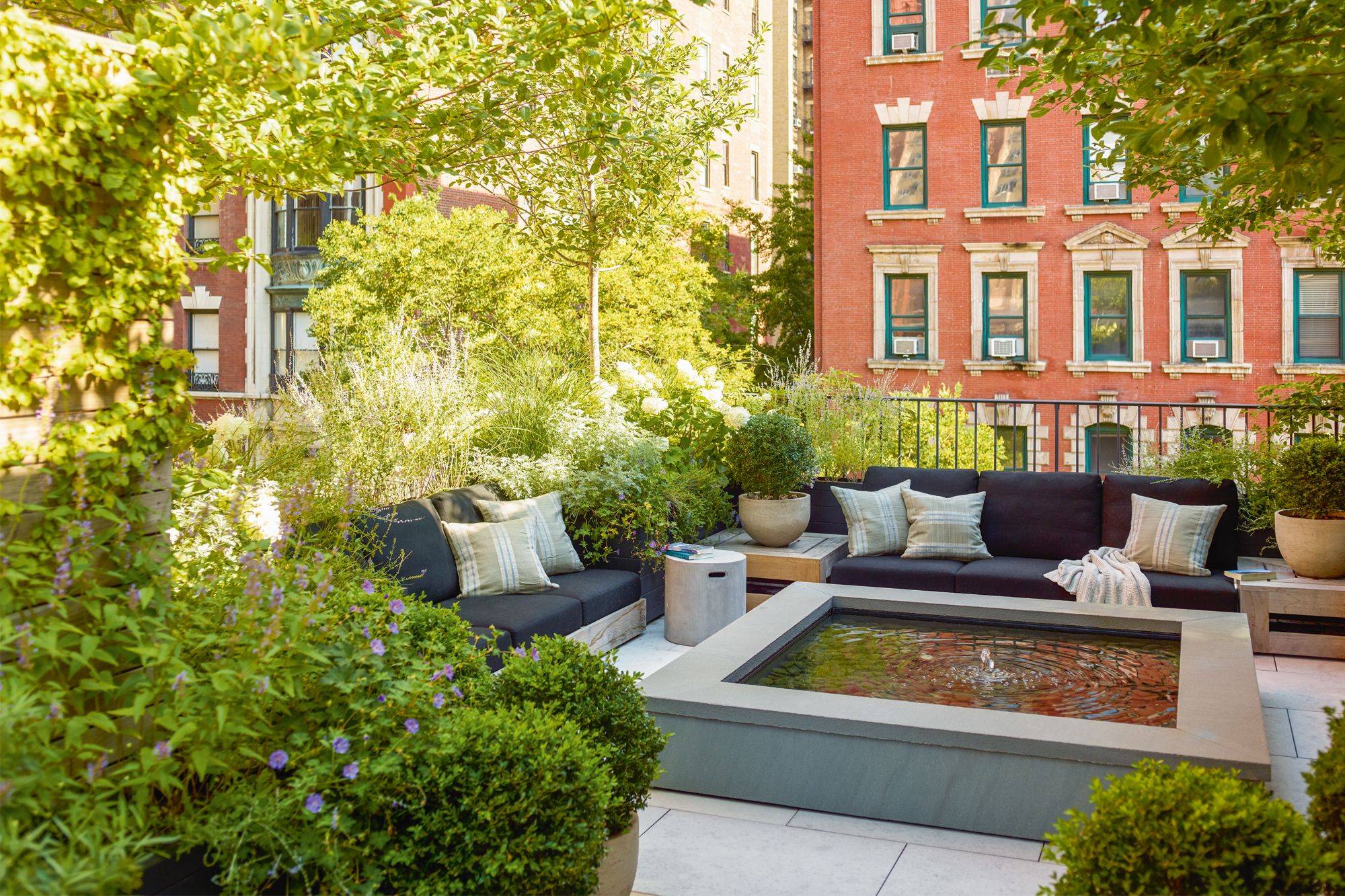 A water feature and flourishing greenery create a calming rooftop sanctuary