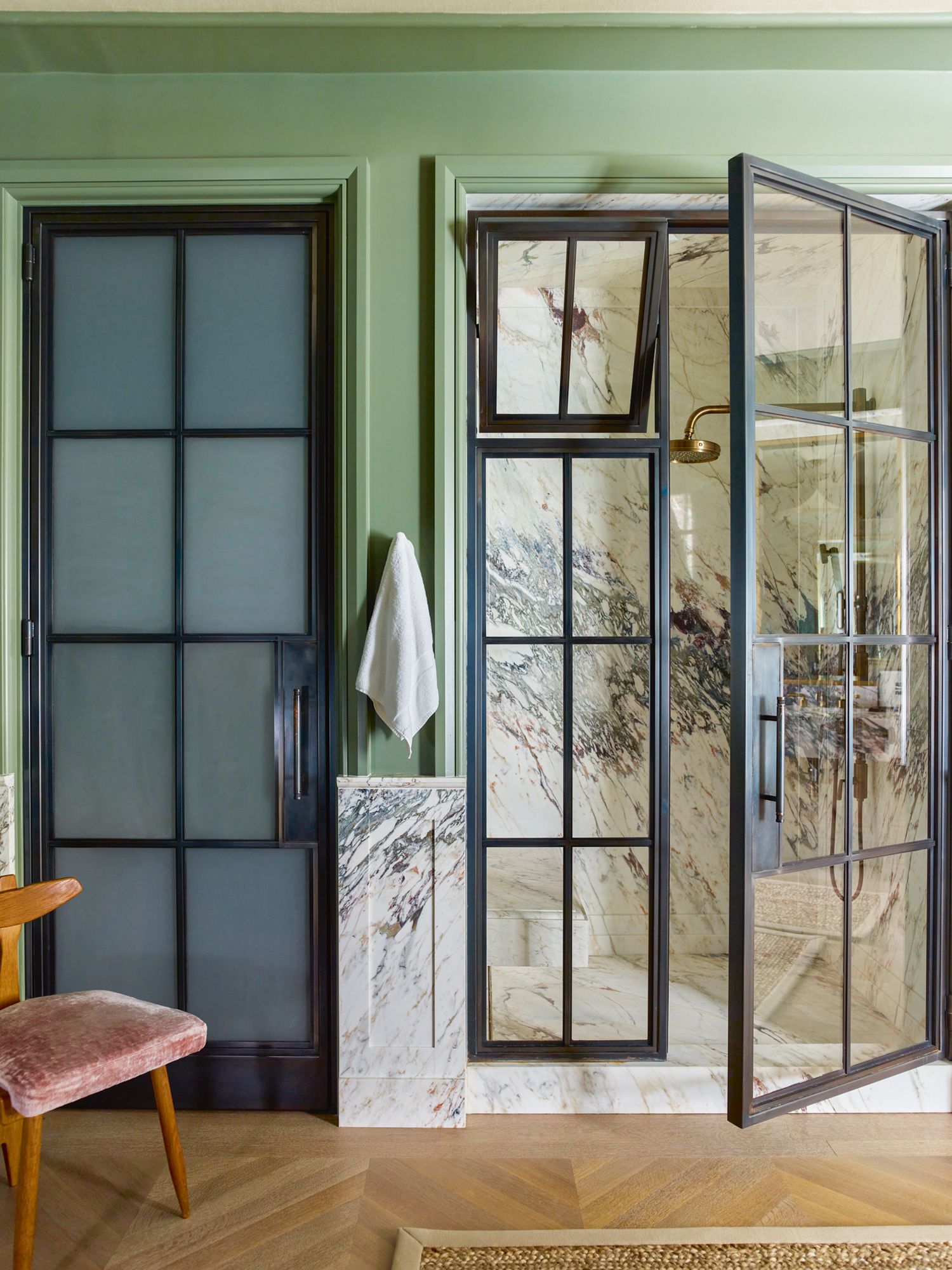 The bathroom also features a vanity and shower area clad in beautifully veined marble