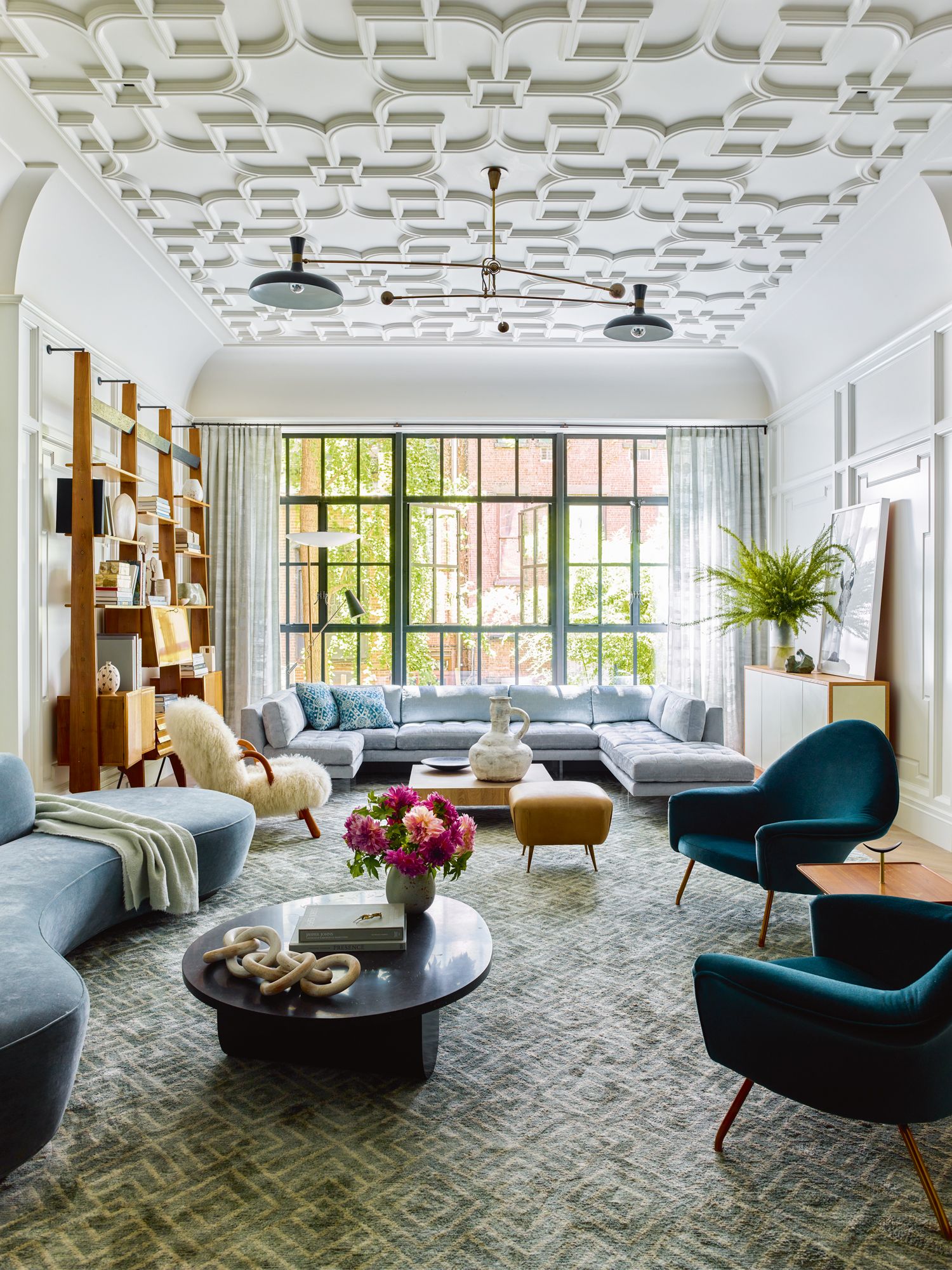 The living room features ornamental plasterwork and full-length windows that overlook the outdoor garden