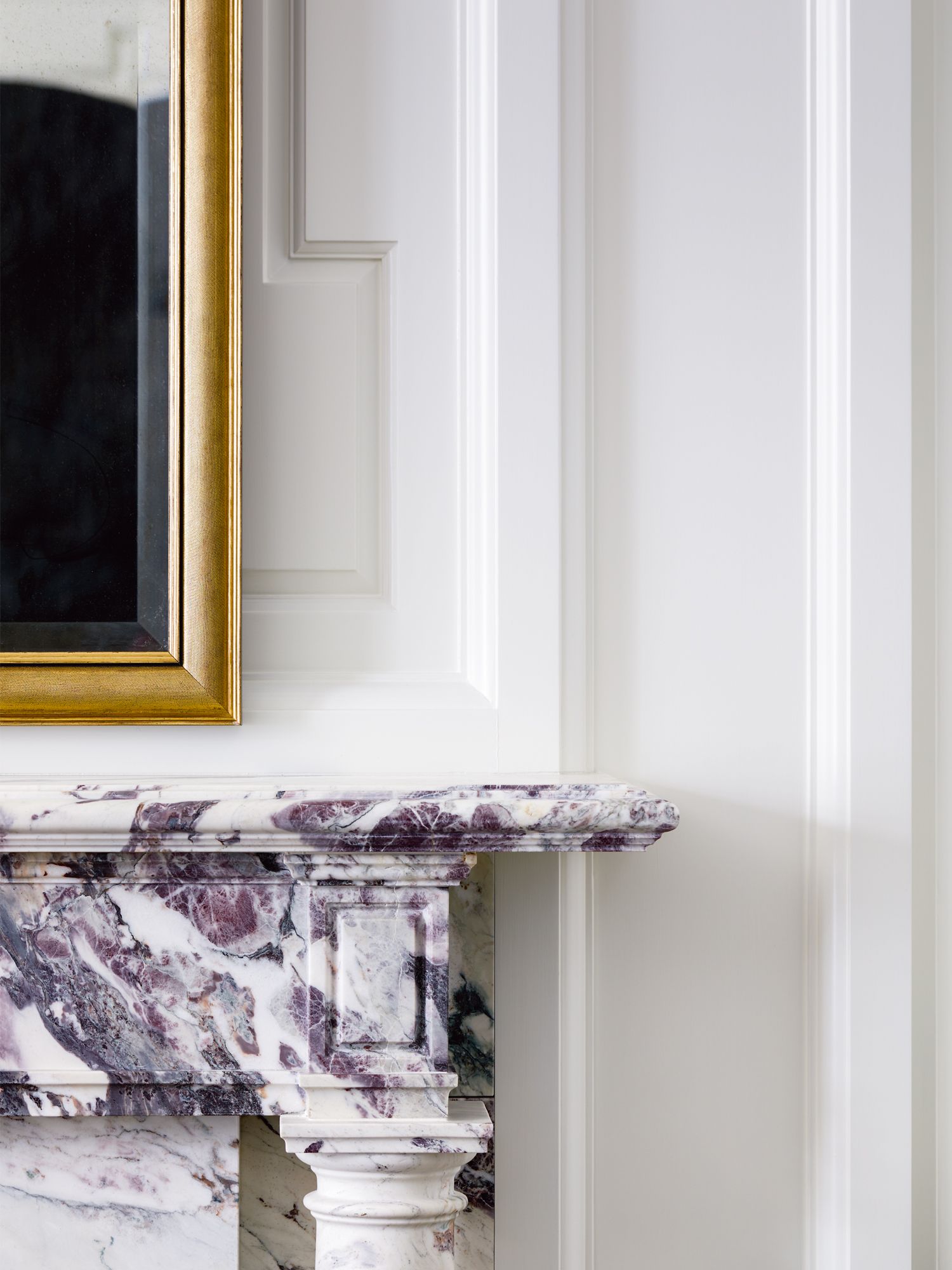 Set against elegant wall mouldings is a custom fireplace made of Breccia Capraia marble