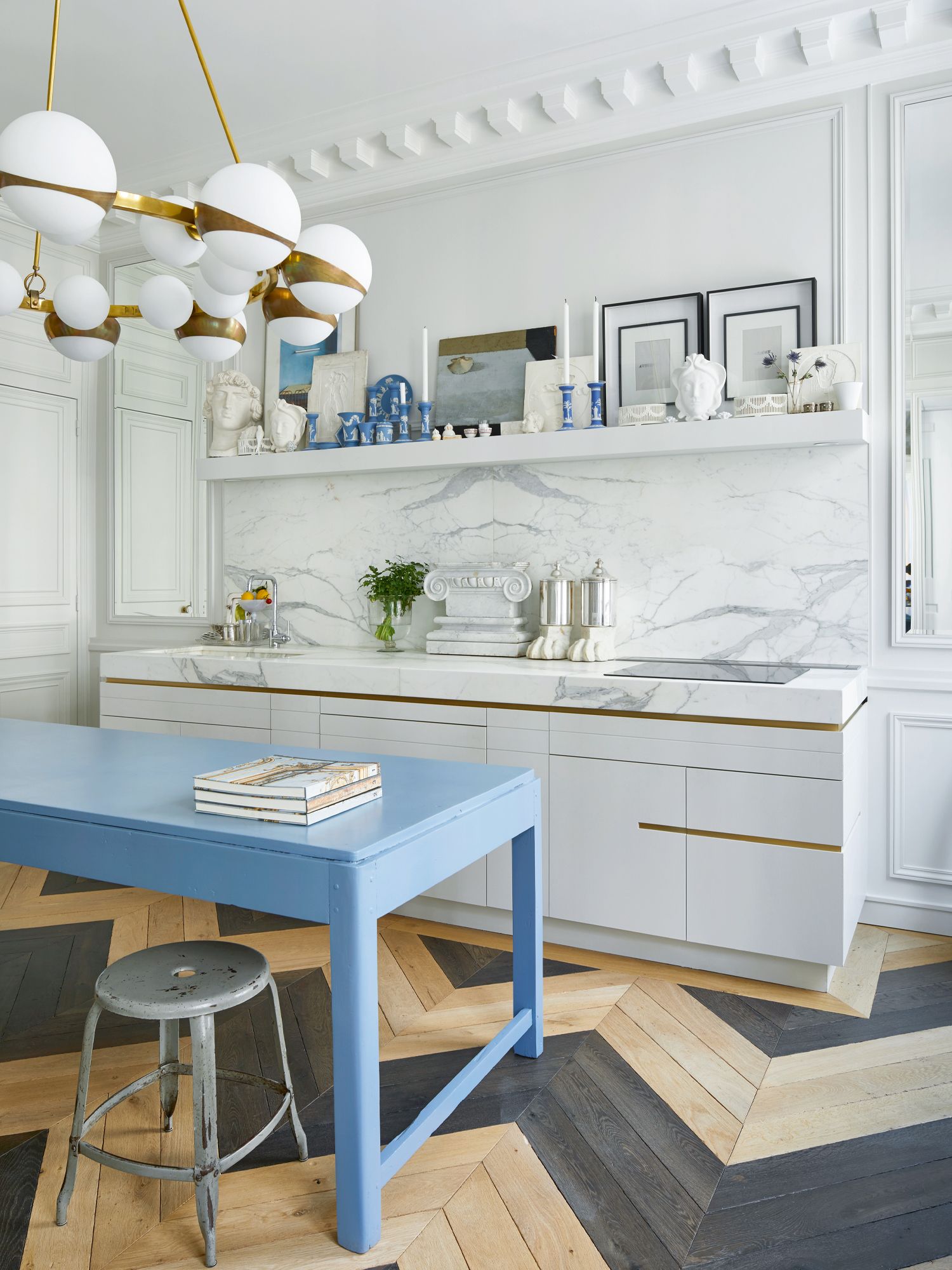The Calacatta marble backsplash and sky blue dining table add visual interest to the white kitchen