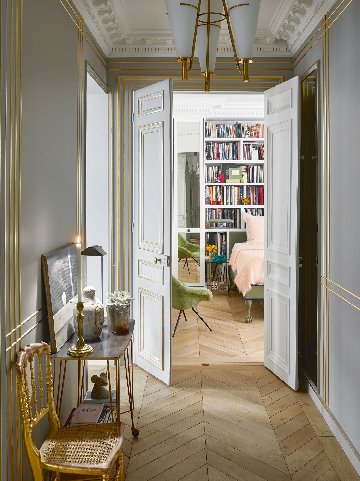 The gold My Dior chair echoes the brass detailing on the console and chandelier overhead, as well as on the walls and doors