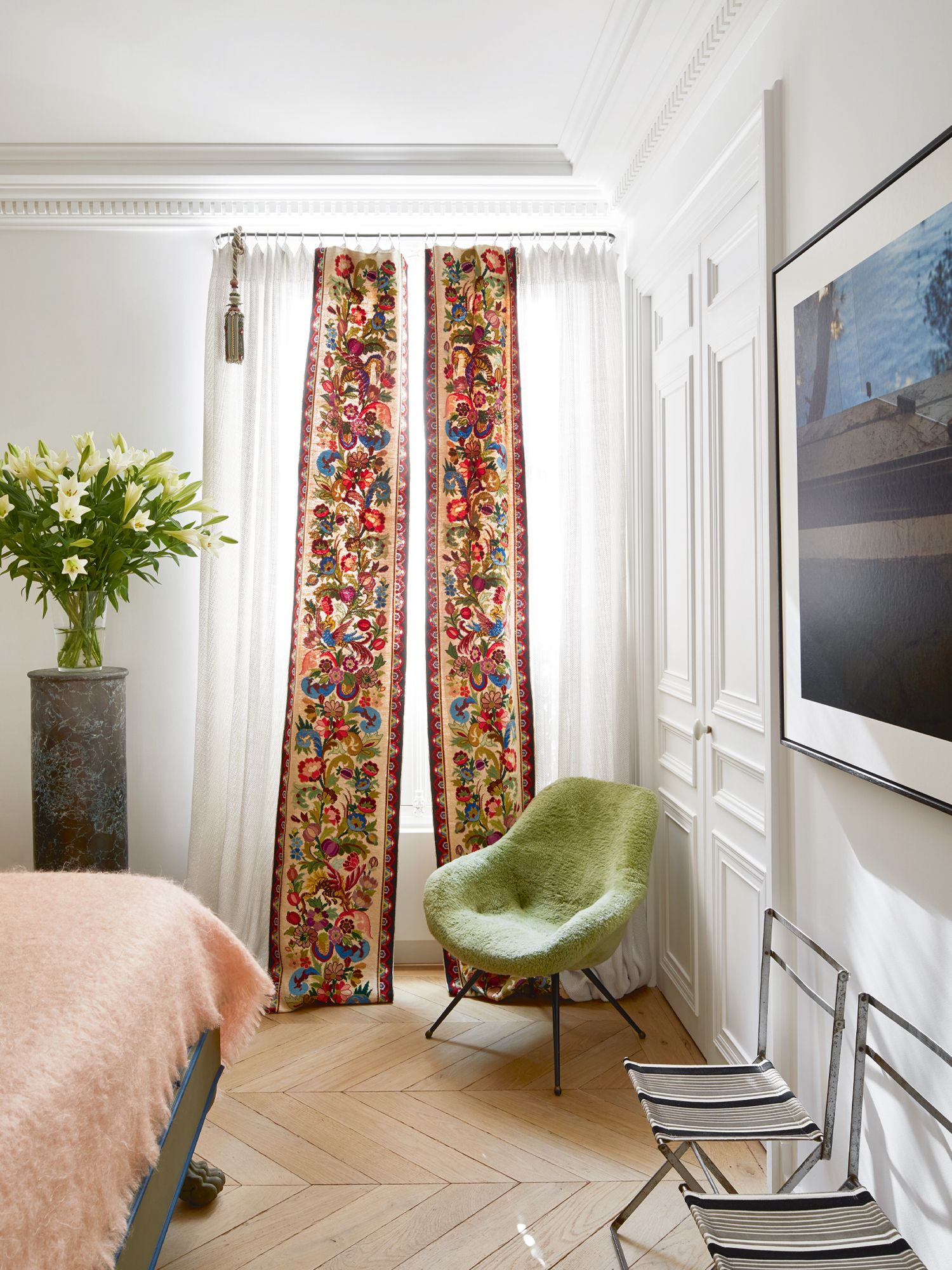 The master bedroom features an Empire-style bed with carved lion’s feet, curtains with 19th-century tapestry work, a pair of Napoleonic military campaign chairs and an armchair in a vintage peluche fabric from the seventies