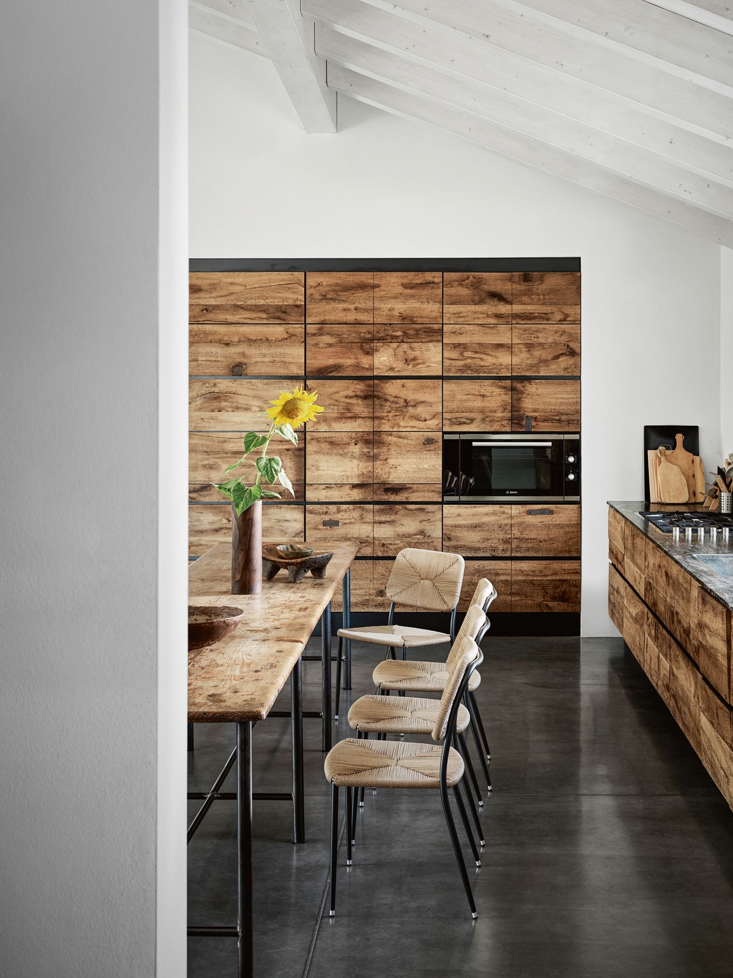 The woven design of the Flexform First Steps chairs by Christophe Pillet fits right in with the wood-panelled kitchen