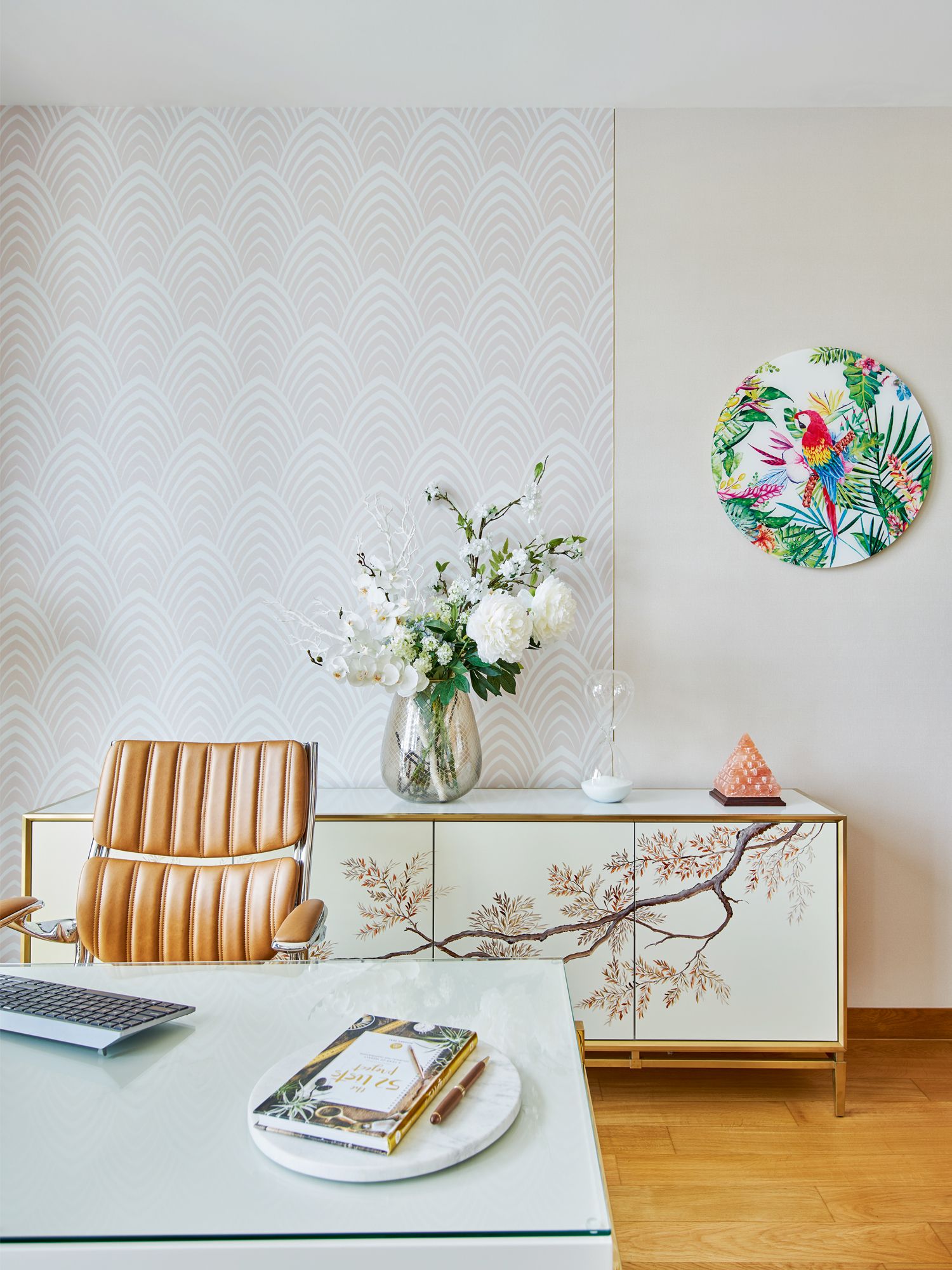Botanical motifs on the artwork and sideboard liven up the study, which also features wallcoverings from Pepperwall