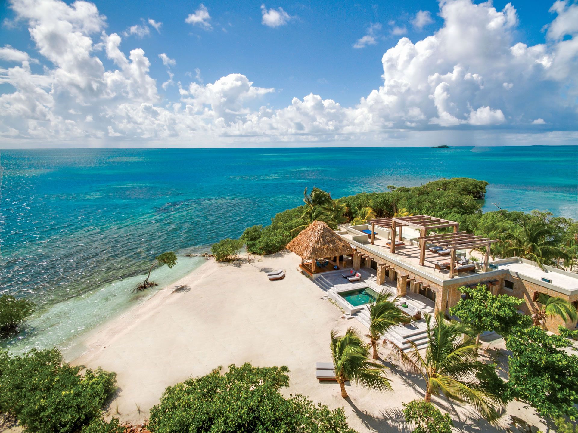 Private tropical island retreat with a beachfront villa, palms, white sand, and turquoise sea