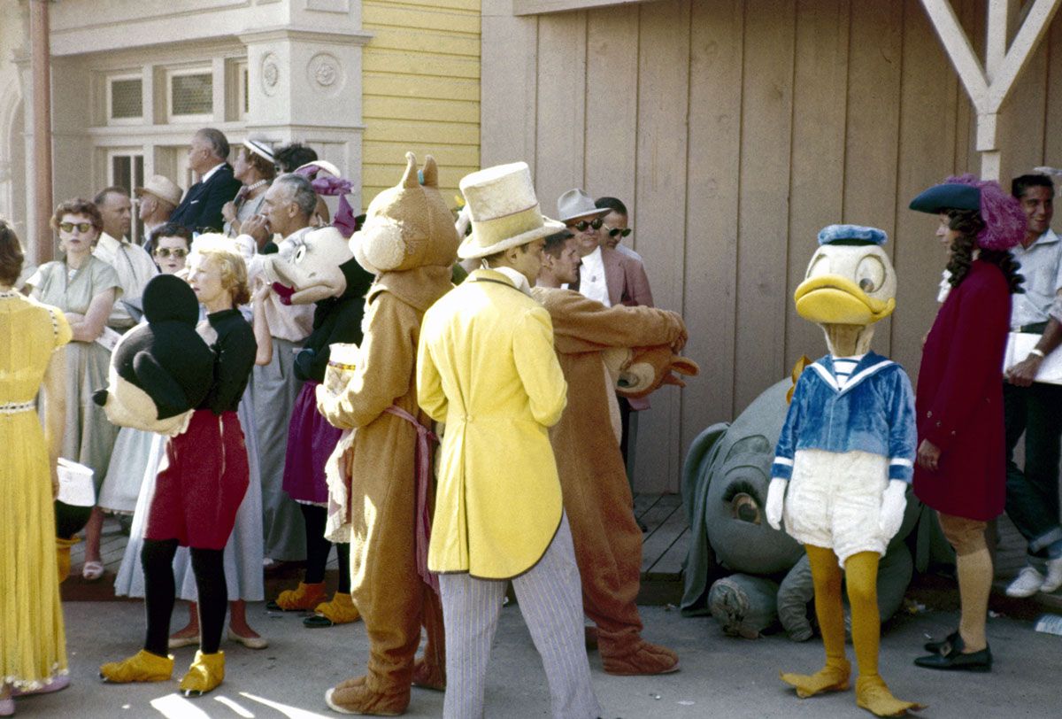 Parade participants ready themselves and their costumes for a the televised grand opening of Disneyland, Anaheim, California July 17, 1955. Minnie and Mickey (the latter with mask off) and Donald Duck are among thoses visible. (Photo by Allan Grant/The LIFE Picture Collection via Getty Images/Getty Images)