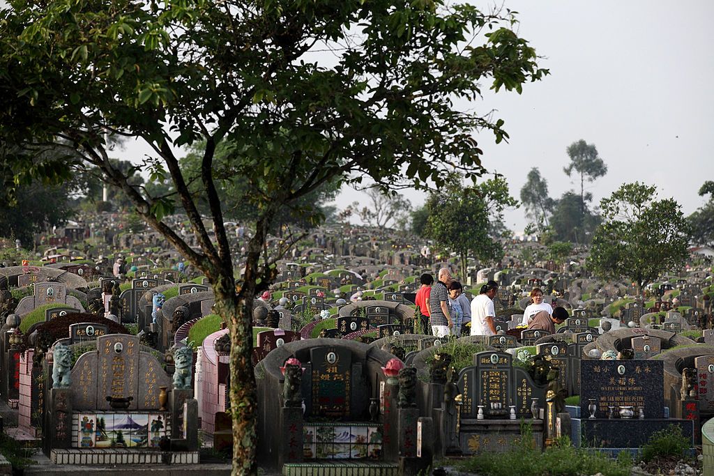 SINGAPORE - APRIL 04: Family members visit the tomb of their loved ones to pay their respects and burn offerings at the Choa Chu Kang Chinese Cemetery during the Qing Ming Festival on April 4, 2013 in Singapore. Qing Ming, also known as Tomb-Sweeping Day, is an annual Chinese festival to commemorate the dead. Families mark the day by visiting and cleaning the graves of their ancestors, burning incense and paper money and presenting offerings such as food, tea, wine and joss paper accessories. (Photo by Su
