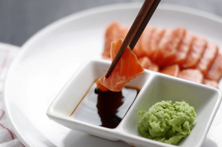 Dipping sliced salmon meat in sauce