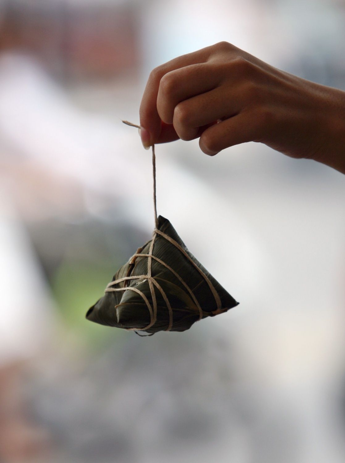 NANJING, CHINA - JUNE 19: (CHINA OUT) A customer displays a rice dumpling called "Zongzi", on Duanwu Festival, or the Dragon Boat Festival today, at a shop June 19, 2007 in Nanjing of Jiangsu Province, China. The Duanwu Festival is celebrated throughout China every year with activities such as boat races and the eating of Zongzi. The festival falls on the fifth day of the fifth lunar month and was established in remembrance of Qu Yuan, a patriotic poet who committed suicide in the Miluo River on the day in