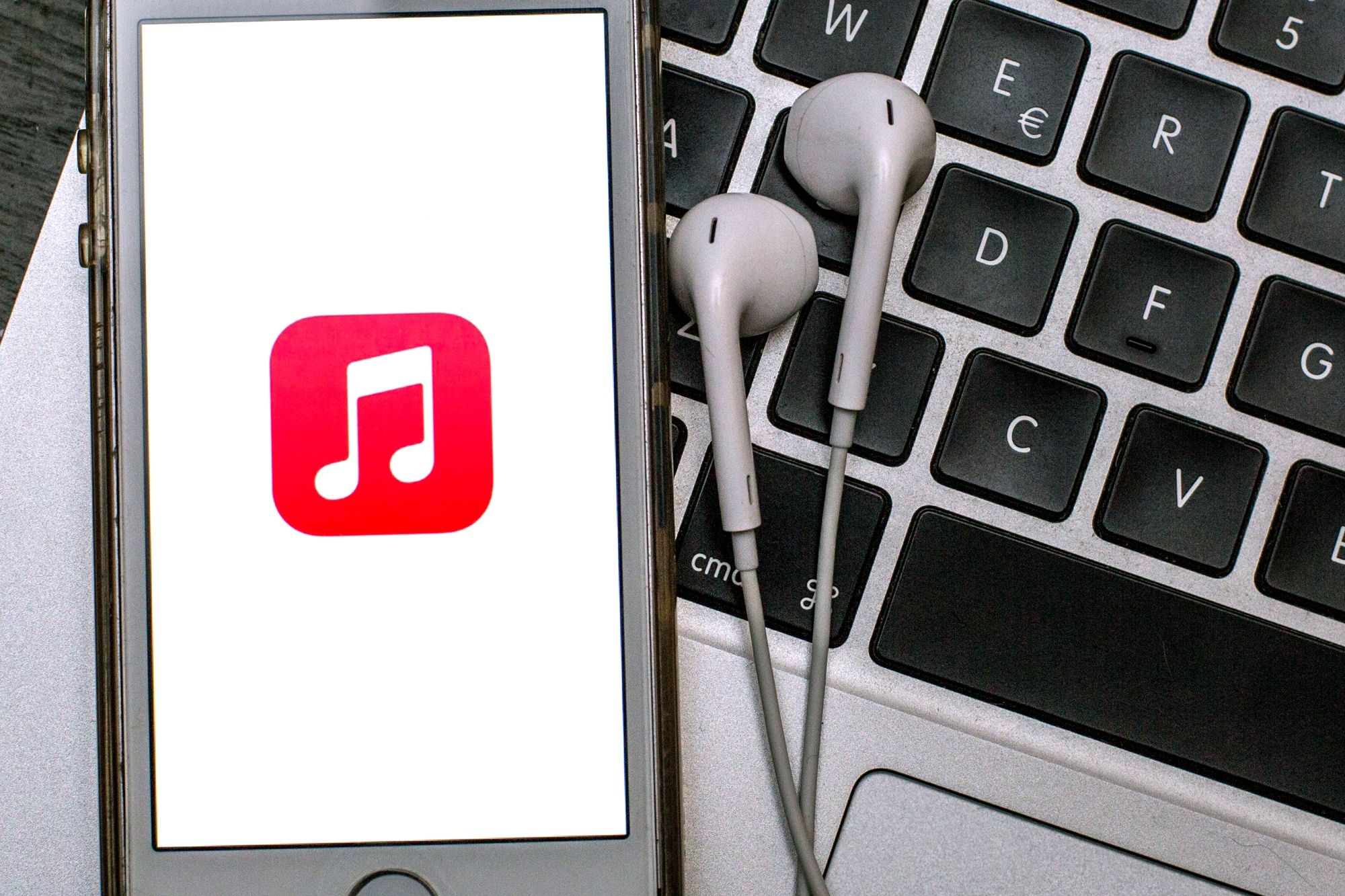 SPAIN - 2021/04/12: In this photo illustration the Apple Music app seen displayed on a smartphone screen with headphones on a laptop keyboard. (Photo Illustration by Thiago Prudencio/SOPA Images/LightRocket via Getty Images)