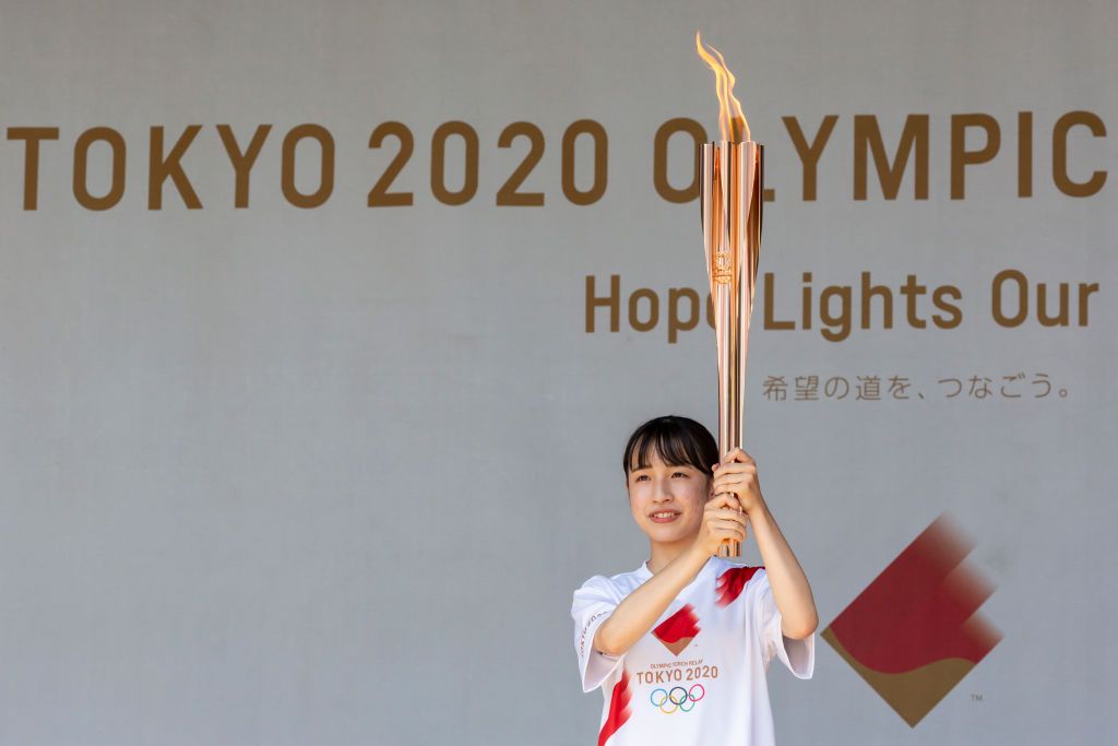 TOKYO, JAPAN - JULY 19: A torch bearer with the Olympic flame poses for photographs during the Olympic Torch Relay Celebration event on July 19, 2021 in Tokyo, Japan. As the Olympic torch relay makes its way around Tokyo, public relays have been cancelled in favour of daily ceremonies held behind closed doors, as authorities act to avoid large gatherings while the country endures a fourth wave of coronavirus. (Photo by Yuichi Yamazaki/Getty Images)