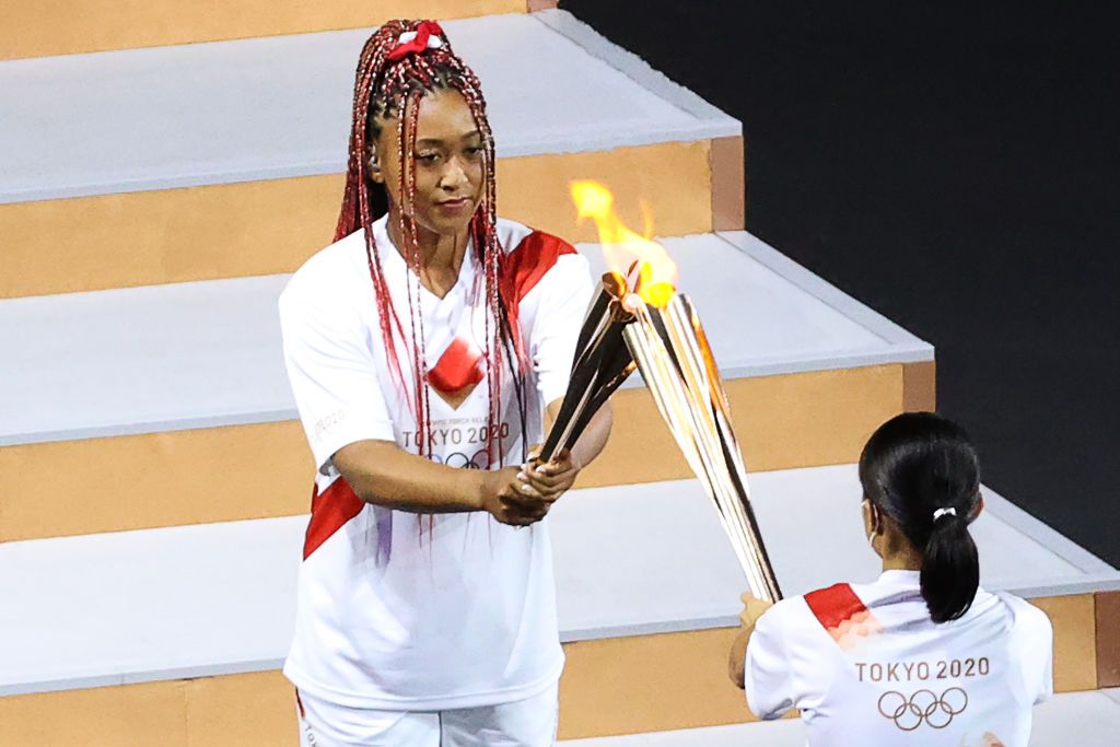 TOKYO, JAPAN JULY 23, 2021: Tennis player Naomi Osaka (L) carries the Olympic torch during the opening ceremony of the Tokyo 2020 Summer Olympic Games at the National Stadium. Tokyo was to host the 2020 Summer Olympics from 24 July to 9 August 2020, however because of the COVID-19 pandemic the games have been postponed for a year and are due to take place from 23 July to 8 August 2021. Stanislav Krasilnikov/TASS (Photo by Stanislav Krasilnikov\TASS via Getty Images)