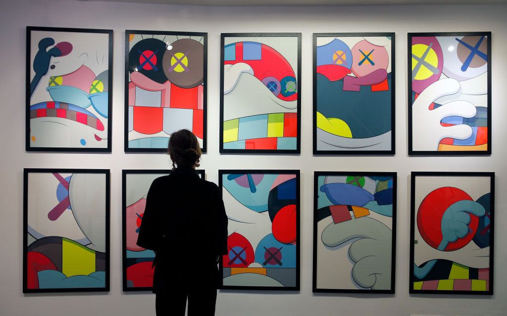 PARIS, FRANCE - OCTOBER 02: A visitor looks at an artwork entitled "Back Game" by US artist Kaws estimated between 80 000 - 100 000 â¬ is displayed during the exhibition "Kaws Exclusive" at Digard auction house on October 02, 2020 in Paris, France. Kaws, real name Brian Donnelly, is an American artist and designer who paints, sculpts and creates toys. Pop art and culture permeate his characters, like the Disney-style Companion that resembles the illustrations of Takashi Murakami.The auction will take place